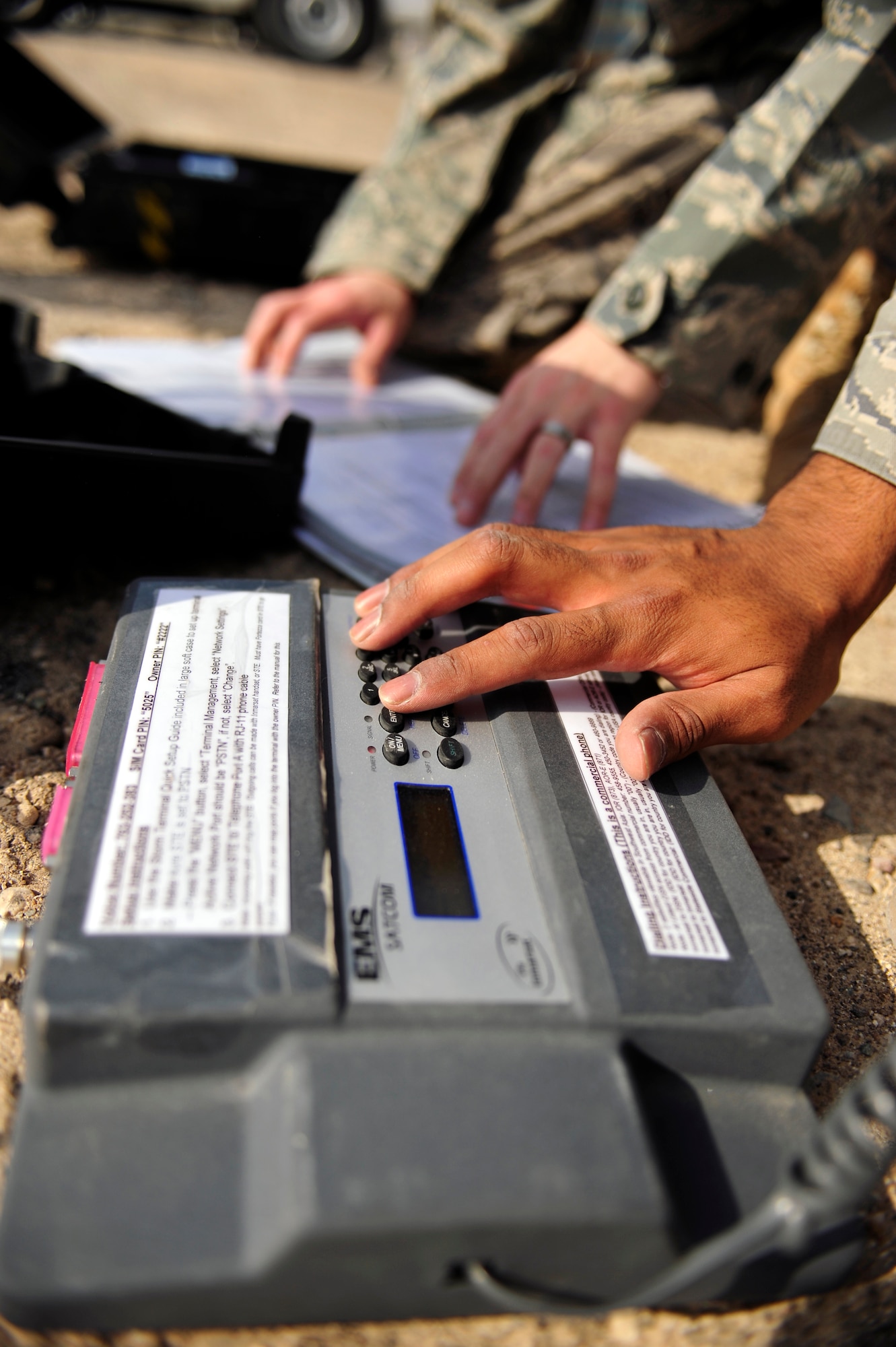SOUTHWEST ASIA -Staff Sgt. Jason Hardman and Senior Airman Jarrett Willis, 380th Communication Squadron, follow the steps in a technical order while testing a satellite phone Aug. 26. Airman Willis is deployed from Royal Air Force Crowghton, England and hails from North Augusta, S.C. Sergeant Hardman is deployed from Hickam Air Force Base, Hawaii and grew up in Hilo, Hawaii. (U.S. Air Force photo/Tech. Sgt. Charles Larkin Sr)