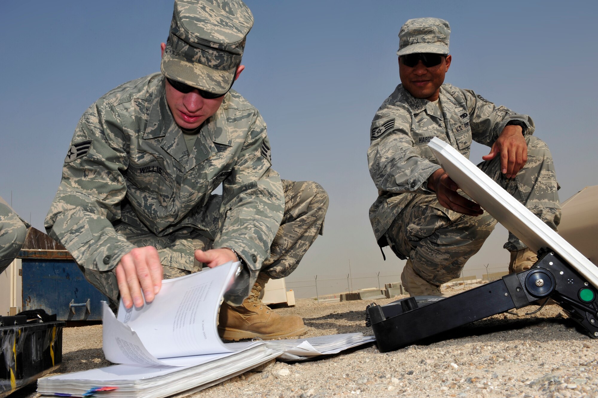 SOUTHWEST ASIA -Senior Airman Jarrett Willis and Staff Sgt. Jason Hardman, 380th Expeditionary Communication Squadron, review a technical order while operating a satellite phone Aug. 26. Airman Willis is deployed from Royal Air Force Crowghton, England and hails from North Augusta, S.C. Sergeant Hardman is deployed from Hickam Air Force Base, Hawaii and grew up in Hilo, Hawaii. (U.S. Air Force photo/Tech. Sgt. Charles Larkin Sr)