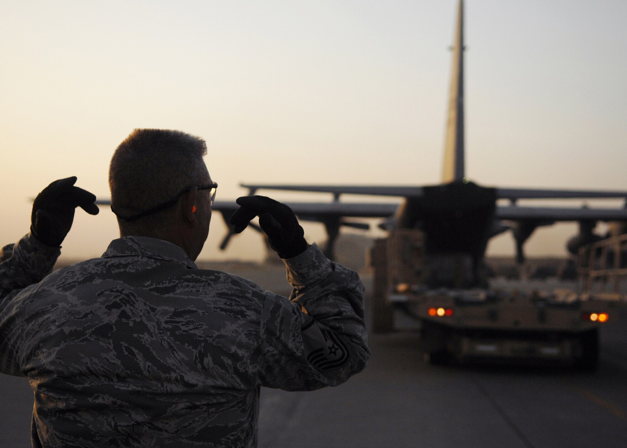 JOINT BASE BALAD, Iraq -- Master Sgt. Mark Groshek, 332nd Expeditionary Logistics Readiness Squadron aircraft service superintendent, helps guide a 60K Tunner away from a C-130 Hercules at the north ramp here Aug. 26, 2009. The 332nd ELRS works with C-5 Galaxies, C-130 Hercules, and C-17 Globemasters. (U.S. Air Force photo/Senior Airman Christopher Hubenthal)