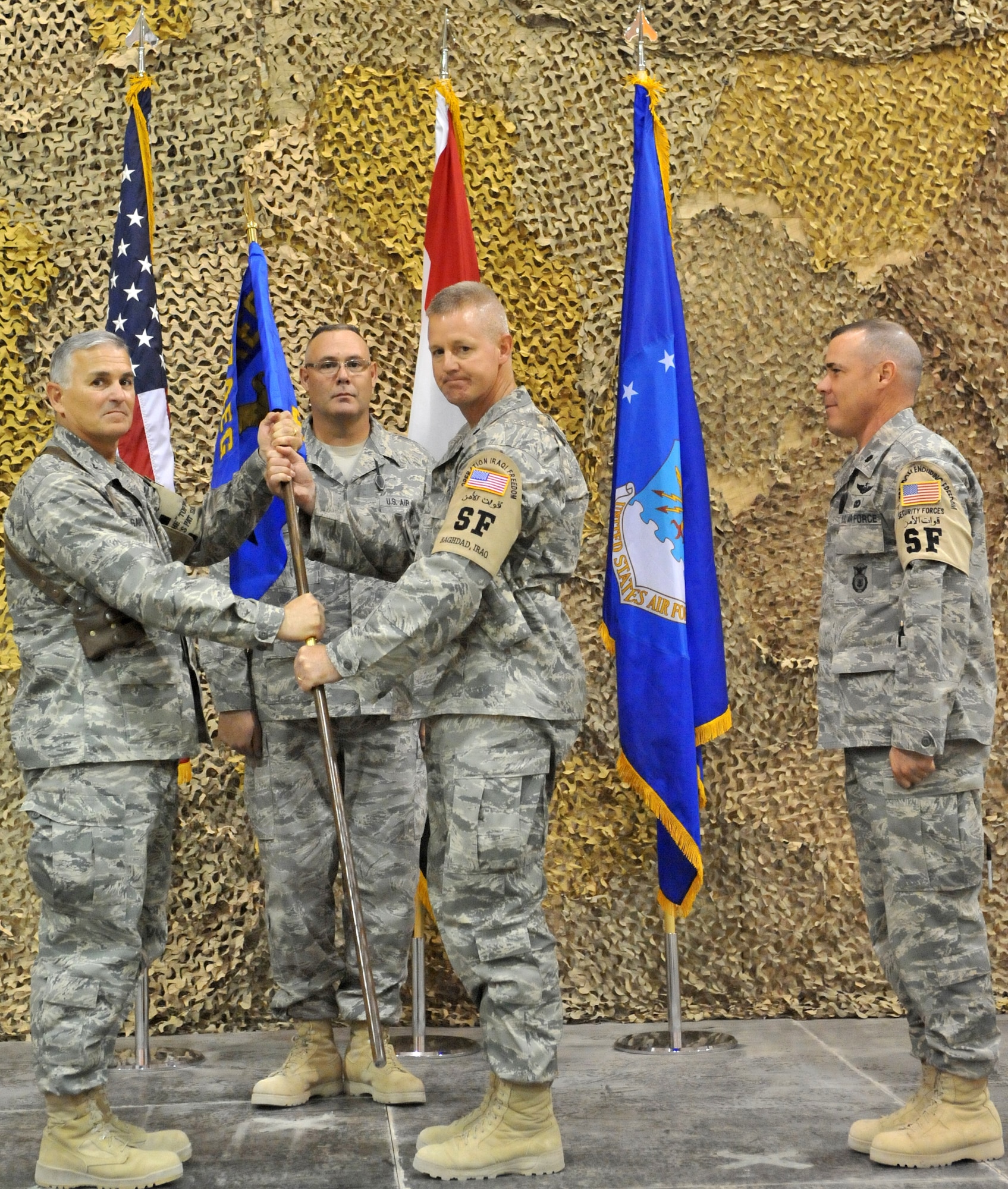 SATHER AIR BASE, Iraq, - Col. Pat Savoy, 447th Air Expeditionary Group commander, passes the 447th ESFS guiedon off to Lt. Col. David Knight, incoming 447th Expeditionary Security Forces Squadron commander, here Aug. 26. (U.S. Air Force Photo by Staff Sgt. Misty D. Slater)


