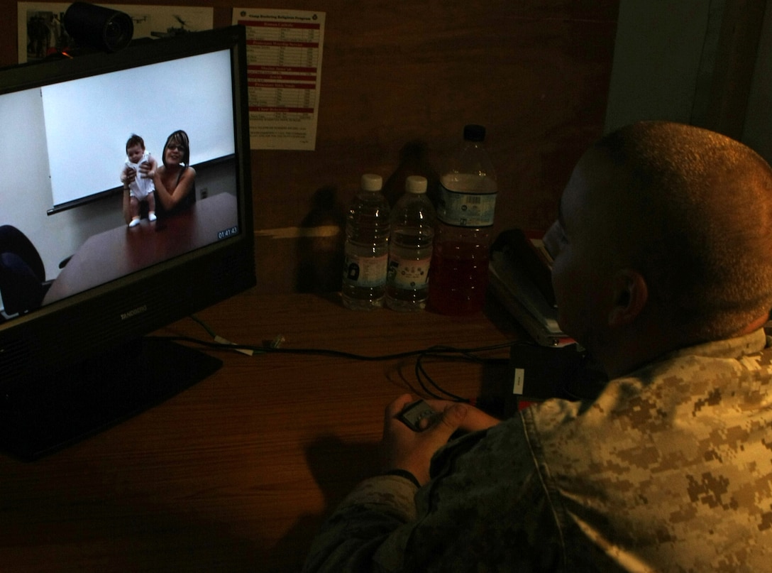 Lance Cpl. John C. Gebelein, a Virginia Beach native and an 81mm mortar forward observer with Kilo Company, Battalion Landing Team, 3rd Battalion, 2nd Marine Regiment, 22nd Marine Expeditionary Unit, says hello to his two-month-old daughter through a Video-Tele-Conference at Camp Buehring, Kuwait Aug. 30, 2009. The 22nd MEU is ashore in Kuwait conducting sustainment training while serving as the theater reserve force for U.S. Central Command.