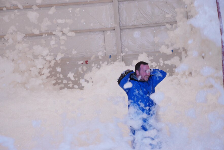 CREECH AFB, Nev. -- Mr. Matthew Fink, 432d Wing Anti-terrorism officer, reaches for his hood during a successful fire-control system test at the newly constructed Hanger 719 Aug. 27.  Mr. Fink volunteered to initiate the foam, which fell at a rate of four feet per minute.  (U.S. Air Force photo by Staff Sgt. Alice Moore)