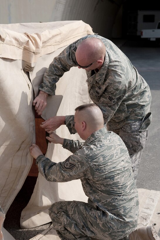 Staff Sgt. Delray Sexton and Senior Airman Shane Shanton assemble a custom tent Aug. 22 in Southwest Asia. The tent is designed to provide shade and respite for flightline maintainers during work-rest cycles in extreme temperatures. Sergeant Sexton is deployed from Holloman Air Force Base, N.M. Airman Shanton is deployed from Kirtland AFB, N.M. Both servicemembers are 379th Expeditionary Operations Support Squadron aircrew flight equipment personnel. (U.S. Air Force Photo/Staff Sgt. Robert Barney)