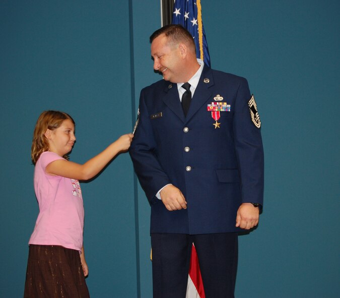 SEYMOUR JOHNSON AIR FORCE BASE, N.C. -- Chief Master Sergeant Dominick Tallarida has his new stripes 'tacked on' by his youngest daughter during his promotion ceremony on Aug. 31.