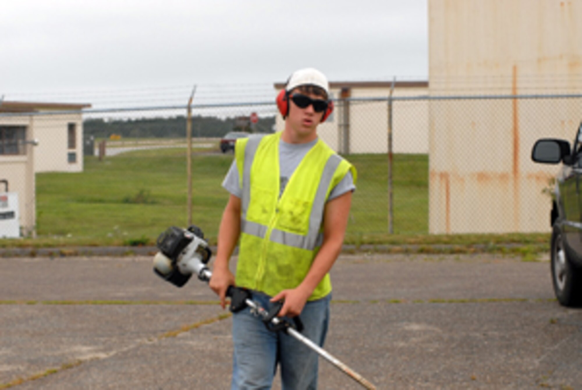 Rylan Richard, 16, prepares to trim the curb side grass outside Building 158 as a Pavement and Grounds summer hire. (U.S. Air Force Photo/Staff Sgt. Kerri Cole)