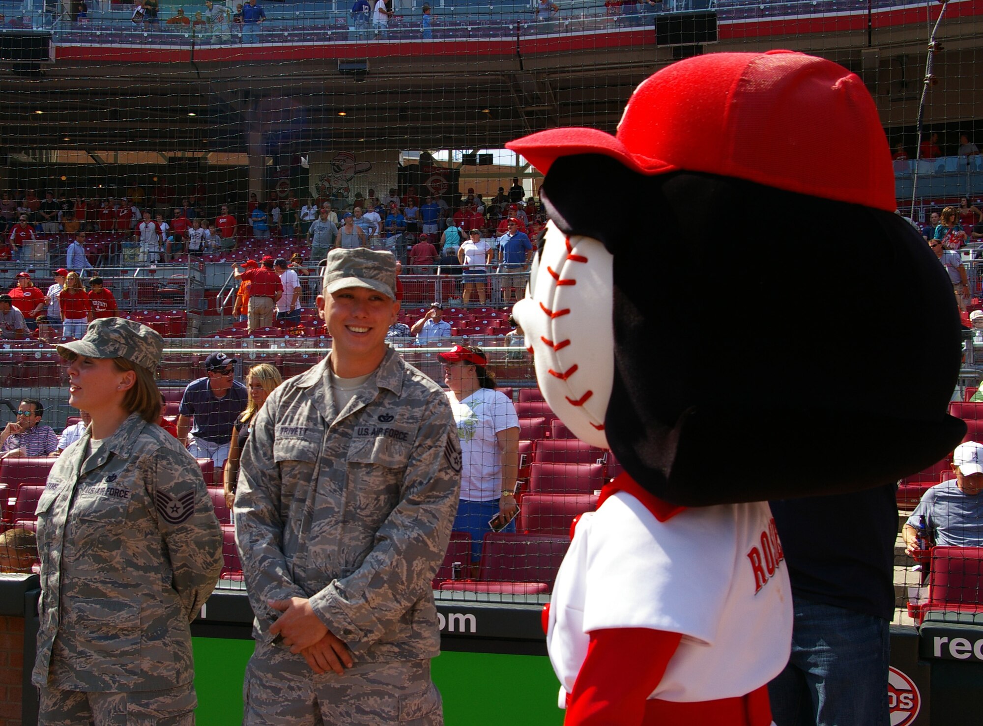 CINCINNATI, Ohio - Staff Sgt. Scott Trivett, 445th Civil Engineer Squadron, smiles at mascot Rosie Red while on the field at the Cincinnati Reds' Great American Ball Park.  Sergeant Scott and Tech. Sgt. Tiffany Watkins (left), both of the civil engineer squadron, were recognized during the pregame ceremony, Aug. 29, 2009, for recently returning from a deployment .  The Saturday game was Cincinnati Reds Military Appreciation Day. (Air Force photo/Laura Darden)  