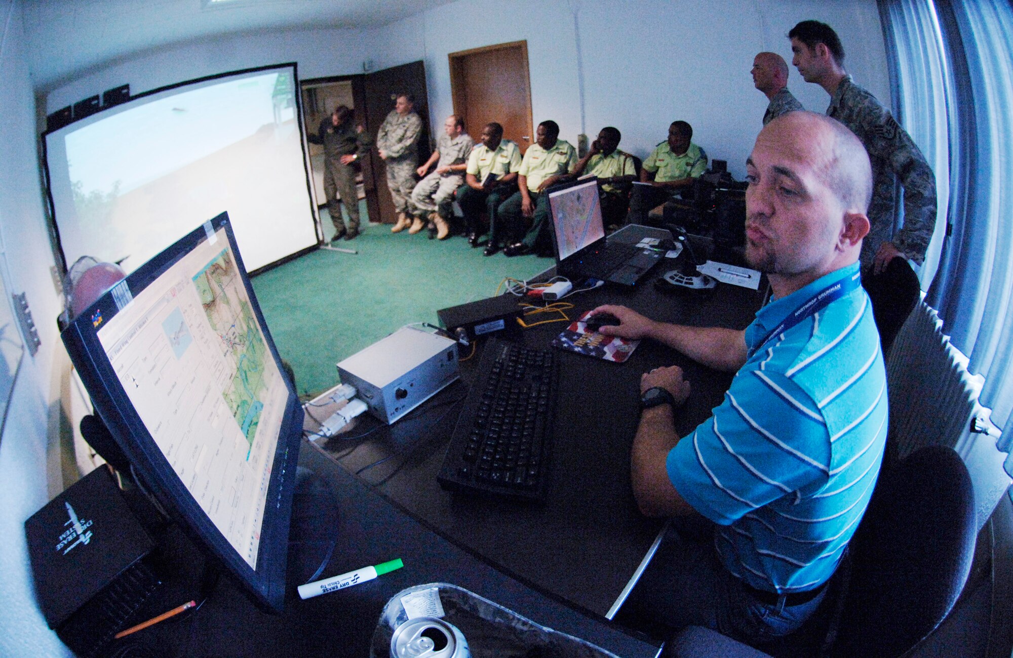 Mr. Casey Ficus works the close-air-support simulator for Lt. Col. Tony Forkner, the commander of the U.S. Air Forces Europe Air Ground Operations School, and guests from Botswana. They are the first African military delegation to visit the facility here. (U.S. Air Force photo'Master Sgt. Donald Wagers)