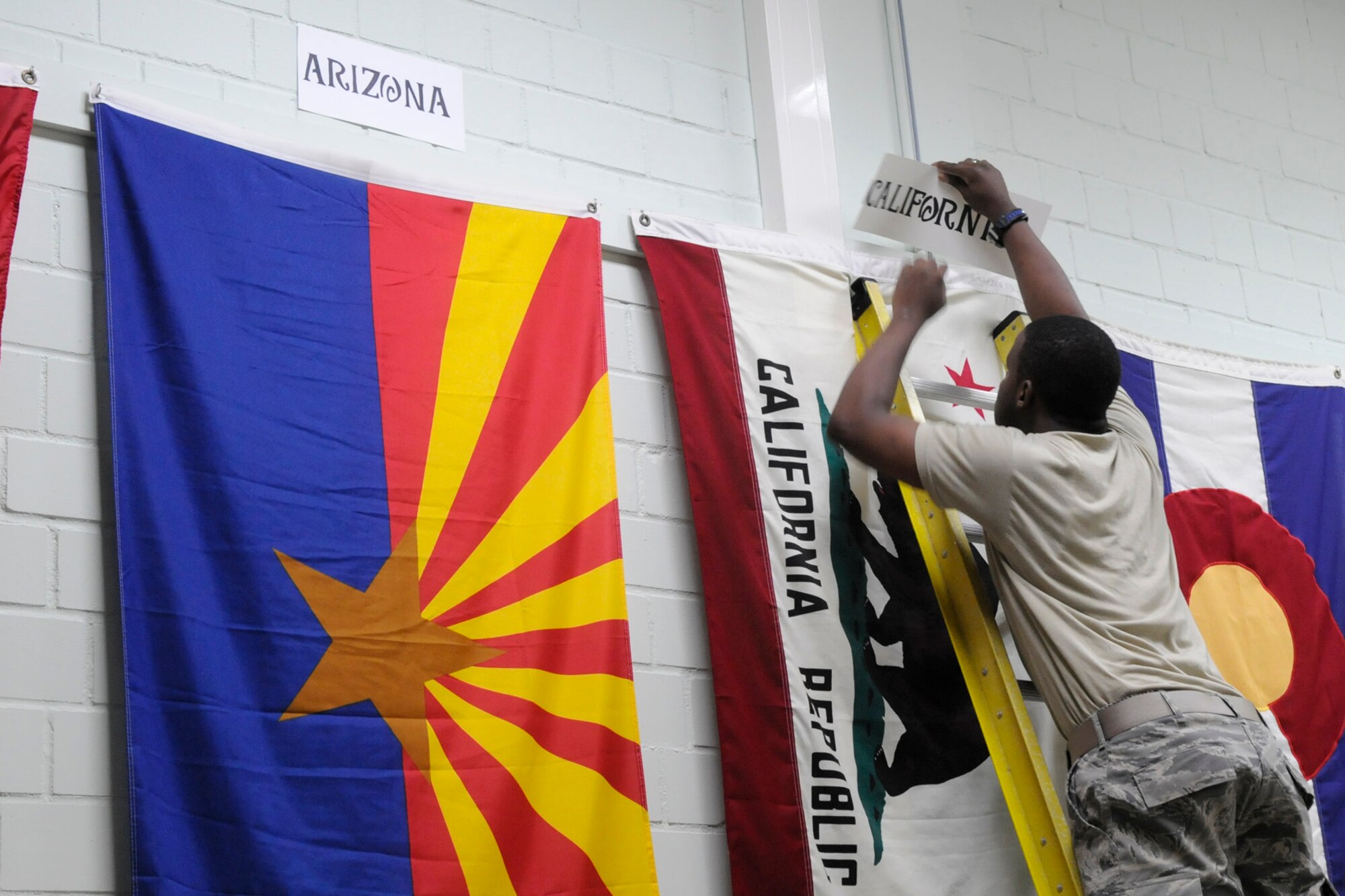 SPANGDAHLEM AIR BASE, Germany – Airman 1st Class Christopher Gilbert, 52nd Force Support Squadron, labels the Californian state flag as part of the Air Force Sergeants’ Association Chapter 1681 Spangdahlem Elementary School state flag project Aug 28. Twenty-two AFSA members hung and labeled all state and territory flags in the Spangdahlem Elementary School gym and presented a scrap book to the school.  (U.S. Air Force photo/Airman 1st Class Staci Miller)