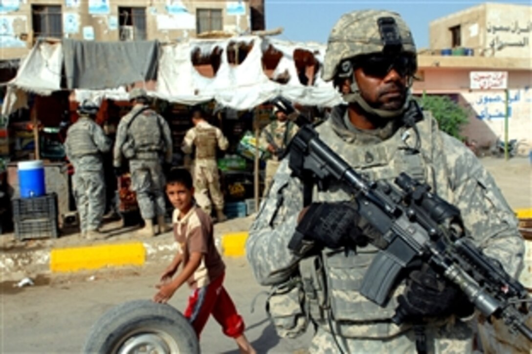 An Iraqi boy rolls a tire behind  U.S. Army Staff Sgt. Kevin Foxworth during a joint patrol with Iraqi army soldiers in a market in southeastern Baghdad, Aug. 18, 2009. Foxworth is an infantry section leader assigned to the 82nd Airborne Division's Company D, 1st Battalion, 505th Parachute Infantry Regiment, 3rd Brigade Combat Team.

