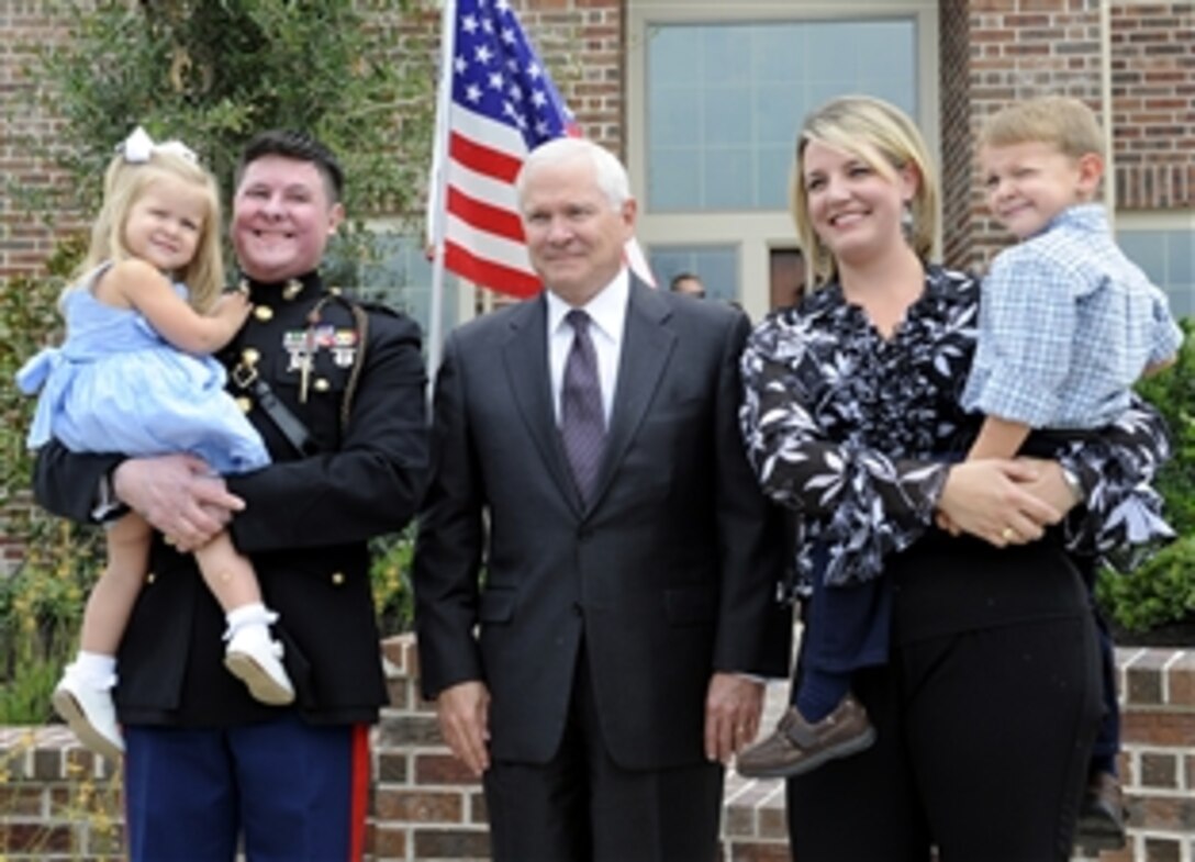 Retired U.S. Marine Capt. Dan Moran, his wife Teal, and their two children Trey and Macy, take a photo with Defense Secretary Robert M. Gates outside his new home built by Perry Homes and Helping a Hero in Cypress, Texas, Aug. 31, 2009.  Helping a Hero is a nonprofit organization that builds specially adapted homes for severely wounded servicemembers injured in theater during the war on terror.  
