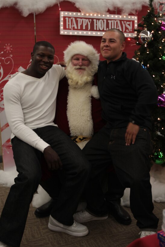 Pvt. Robert Tyree (left) and Pvt. Navarreterios Efrain, both students with Marine Corps Communication-Electronics School, pose with Santa after telling him what they wanted for Christmas during the Single Marine Program Shopping Night Dec. 1.
