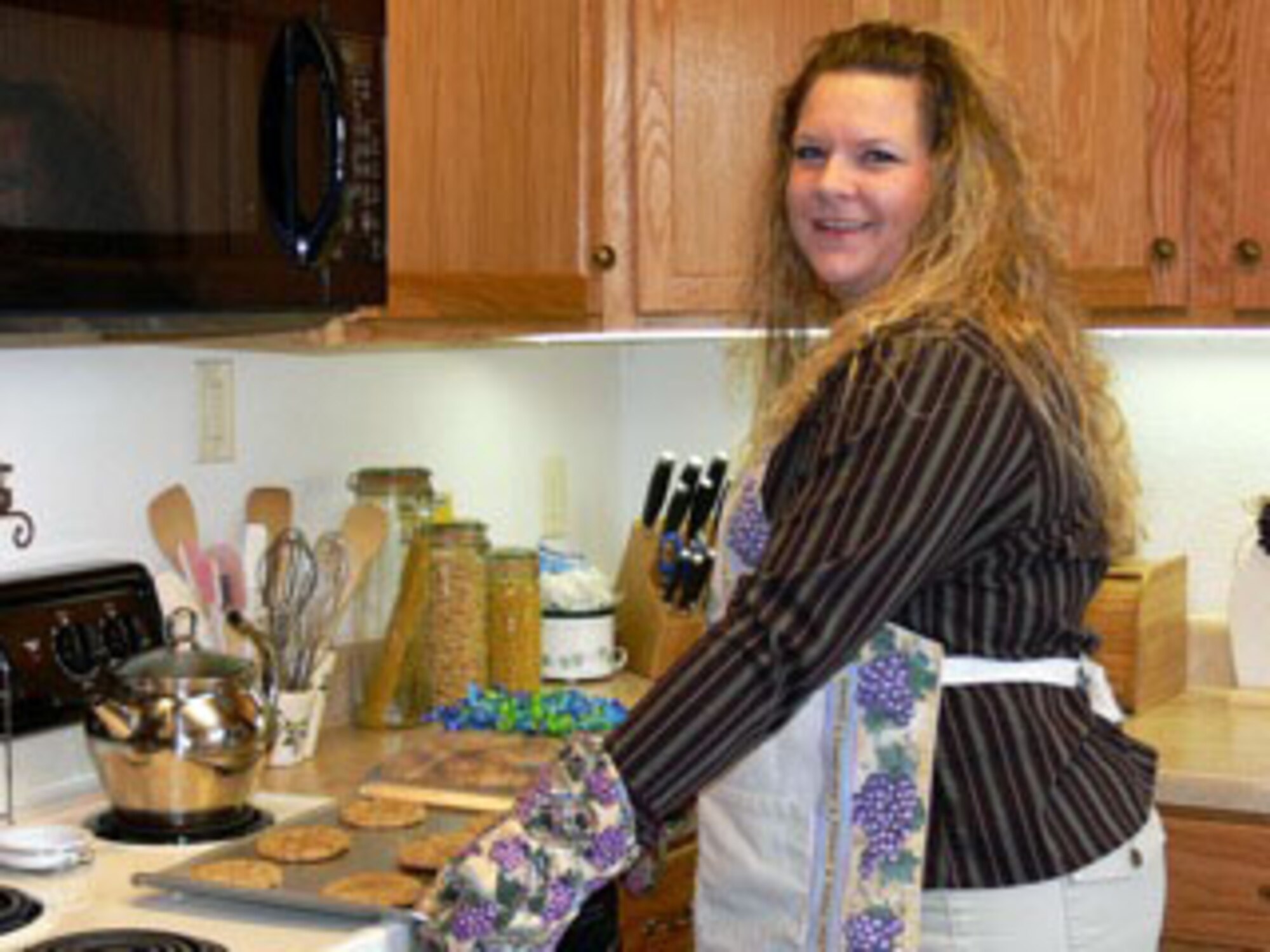 Farrah Champion takes out the last batch of chocolate chip cookies from the oven Nov. 23. Ms. Champion is a member of the Peterson Spouses’ Club and key organizer of this year’s Cookies for Troops holiday cookie give-away. The club will accept cookies from 9 a.m. to 7 p.m. Dec. 7 and 9 a.m. to 4 p.m. Dec. 8 at the chapel, Building 1410 on Stewart Avenue. Cookies will be bagged and delivered to Airmen who live in the dormitories and Airmen who work in 24-hour work stations. Last year, more than 700 dozen cookies were donated and delivered. (Air Force photo by Monica Mendoza)