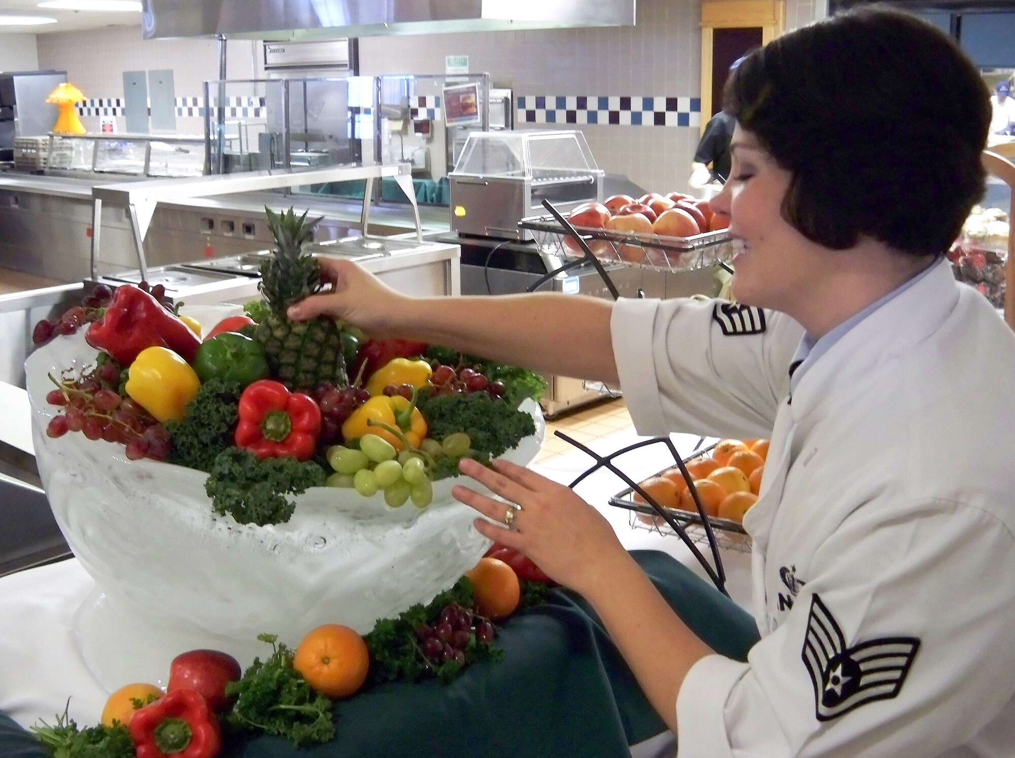 Staff Sgt. Carolina Angulo, 436th Force Support Squadron Patterson Dining Facility manager, places fruit and vegetables into an ice sculpture basket as decoration for the Thanksgiving meal Nov. 26. Patterson Dining Facility workers spent the day prior preparing for the holiday meal. (U.S. Air Force photo/ Airman 1st Class Shen-Chia Chu)