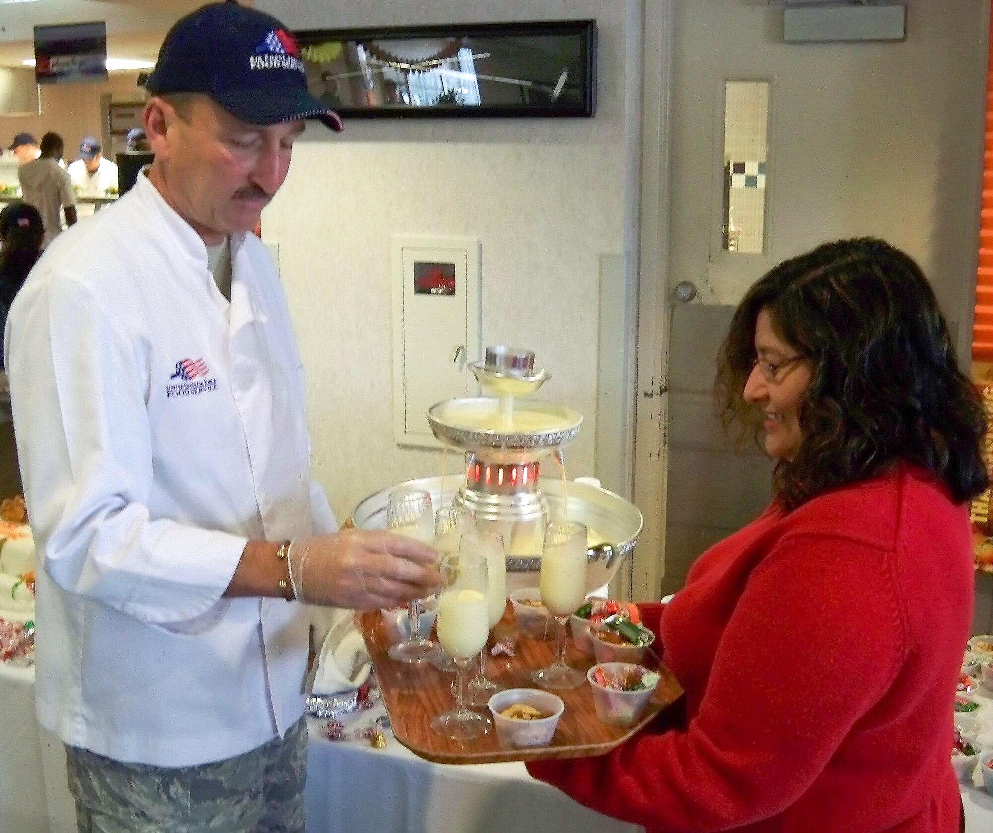 (Left to right) Chief Master Sgt. Fred Eason, 512th Aircraft Maintenance Squadron superintendent, places eggnog on a tray carried by Irene Hafer, wife of Col. David Hafer, 436th Operations Group deputy commander, who served Dover Airmen and retirees eggnog refreshments at the Patterson Dining Facility Nov. 26. Wing leadership volunteered to serve a holiday meal for Team Dover and wish them a Happy Thanksgiving. (U.S. Air Force photo/ Airman 1st Class Shen-Chia Chu)