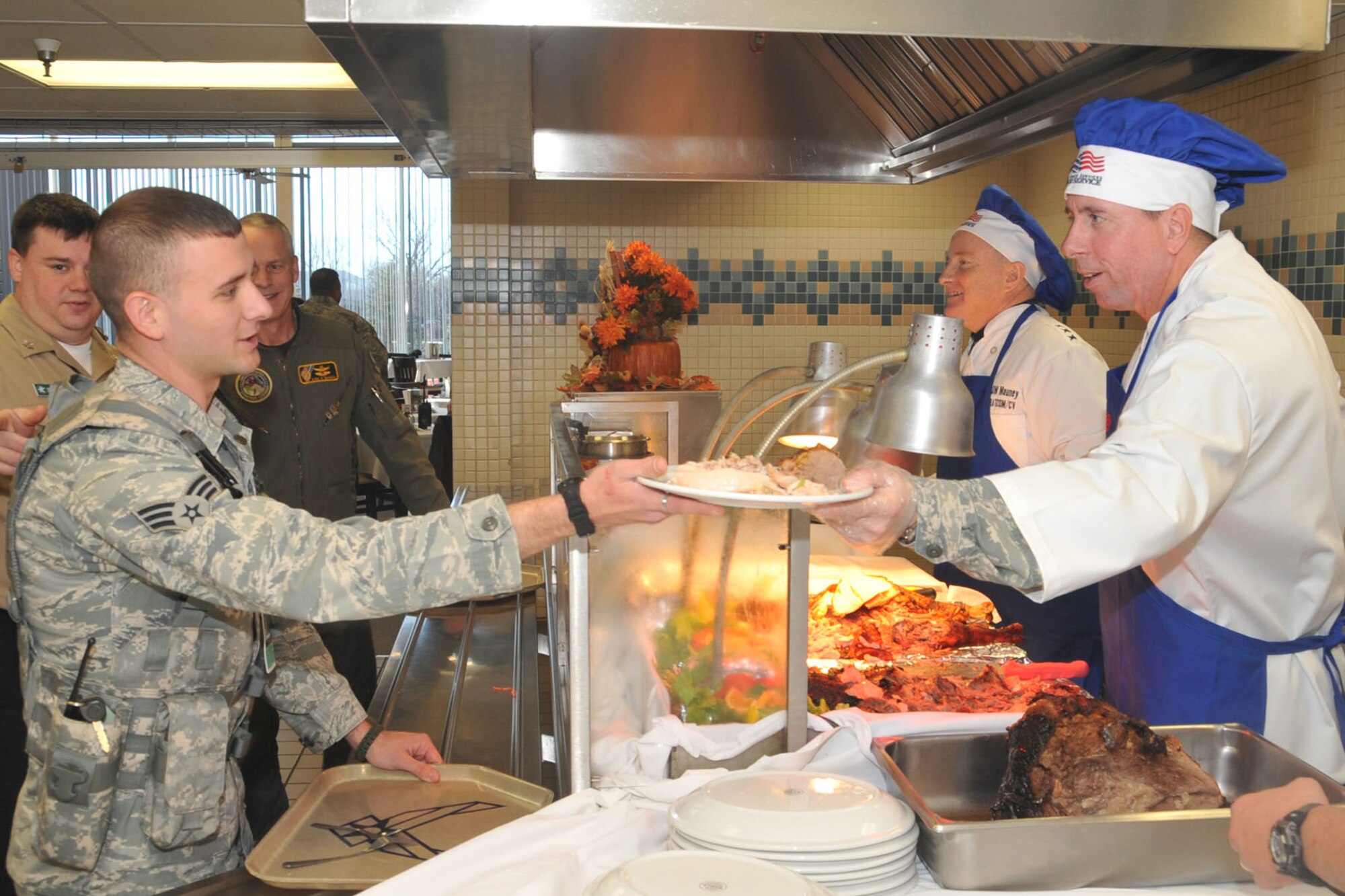 OFFUTT AIR FORCE BASE, Neb. - 55th Wing Commander Brig. Gen. John N.T. Shanahan, hands a plate of food to Senior Airman Chris Patterson, 55th Security Forces Squadron, Nov. 26 at the Campisi Alert Dining Facility during the facility's Thanksgiving meal. General Shanahan and other senior leaders volunteered to serve Thanksgiving meals to members of Team Offutt as a way of thanking them for their service. U.S. Air Force Photo by Stephen Cunningham