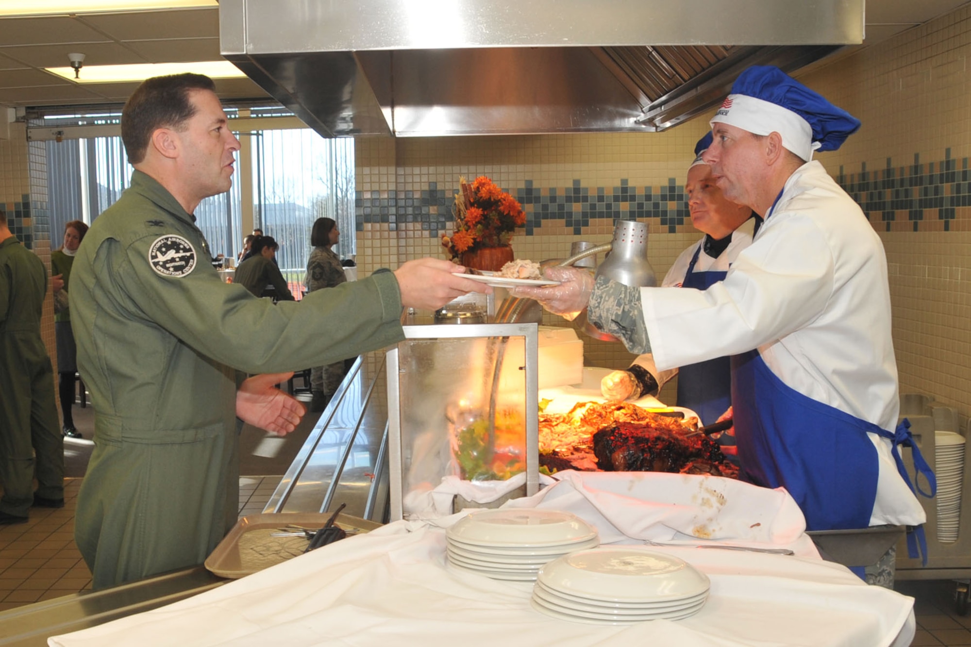 OFFUTT AIR FORCE BASE, Neb. - 55th Wing Commander Brig. Gen. John N.T. Shanahan, hands a plate of food to Col. Marty Doebel, 1st Airborne Command and Control Squadron commander, Nov. 26 at the Campisi Alert Dining Facility, during the facility's Thanksgiving dinner.  General Shanahan and other senior base leaders volunteered to serve Thanksgiving meals to members of Team Offutt as a way of thanking them for their service. U.S. Air Force Photo by Stephen Cunningham