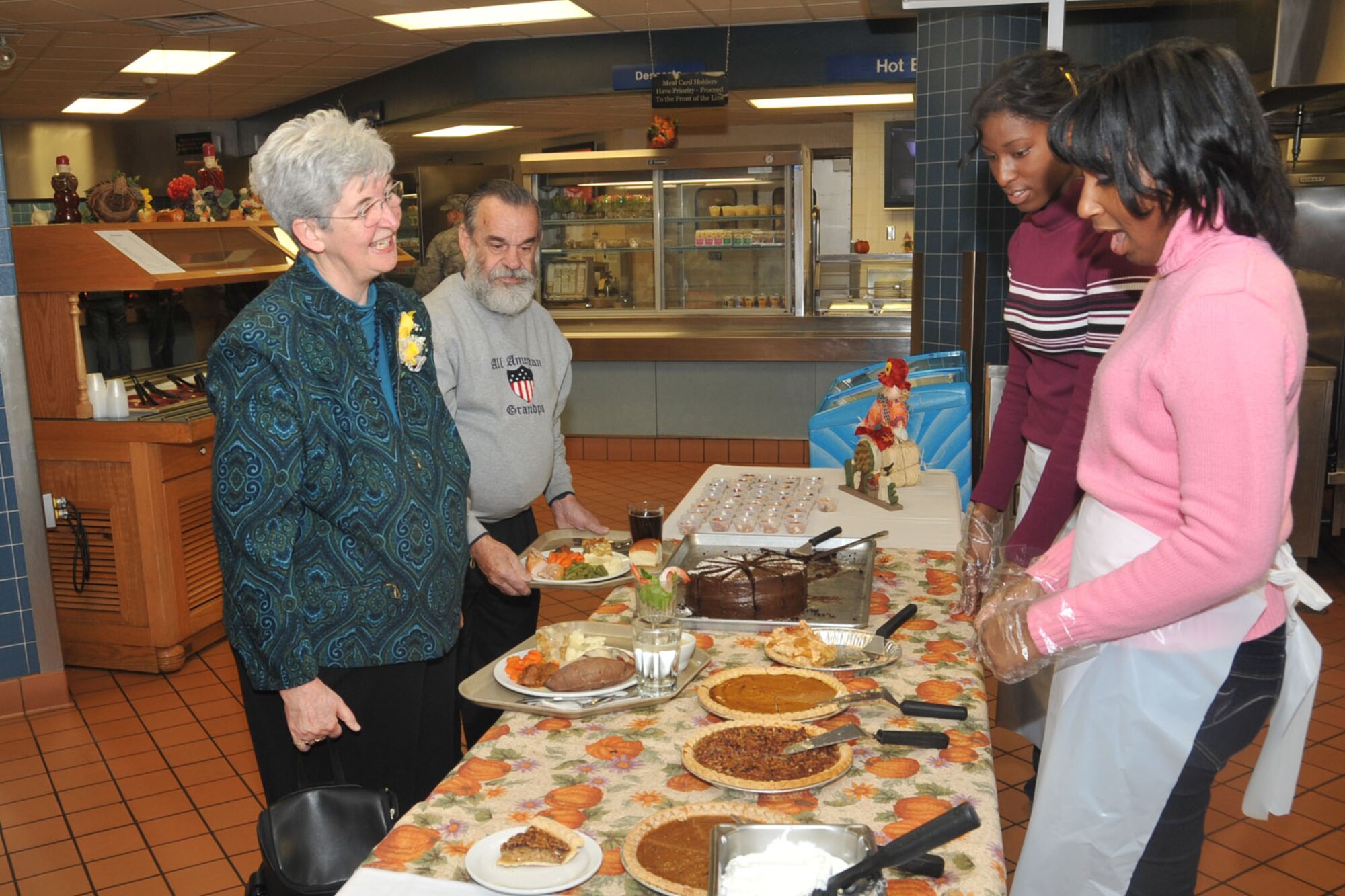 OFFUTT AIR FORCE BASE, Neb. - Carline Hefner and retired Tech. Sgt. David R. Hefner, look at the desert offerings at the King Dining Facility here Nov. 26, during the facility's Thanksgiving dinner, as  Elexis Moble and Amaris Baker, daughters of Chief Master Sgt. Renea Lipscomb, U.S. Strategic Command. Ms. Moble and Ms. Baker volunteered to help serve desert to members of Team Offutt, as well as retired military members and their families, as a way to thank them for their service and sacrafice. The Hefners take part in Offutt's Thanksgiving meal every year. U.S. Air Force Photo by Stephen Cunningham