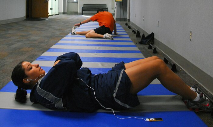 Staff Sgt. Carmen Garrett performs situps before a run on the treadmill while Rudy Gravely stretches out before a strength training workout at the Fitness and Sports Center here Nov. 30. According to base fitness trainers, both cardiovascular training, such as running, and strength training workouts are important for overall physical conditioning and can help keep extra calories from becoming extra pounds during the holiday season. Sergeant Garrett is a vehicle dispatcher with the 437th Logistics Readiness Squadron Vehicle Management Flight and Mr. Gravely is a retired lieutenant colonel. (U.S. Air Force photo/Staff Sgt. Daniel Bowles)