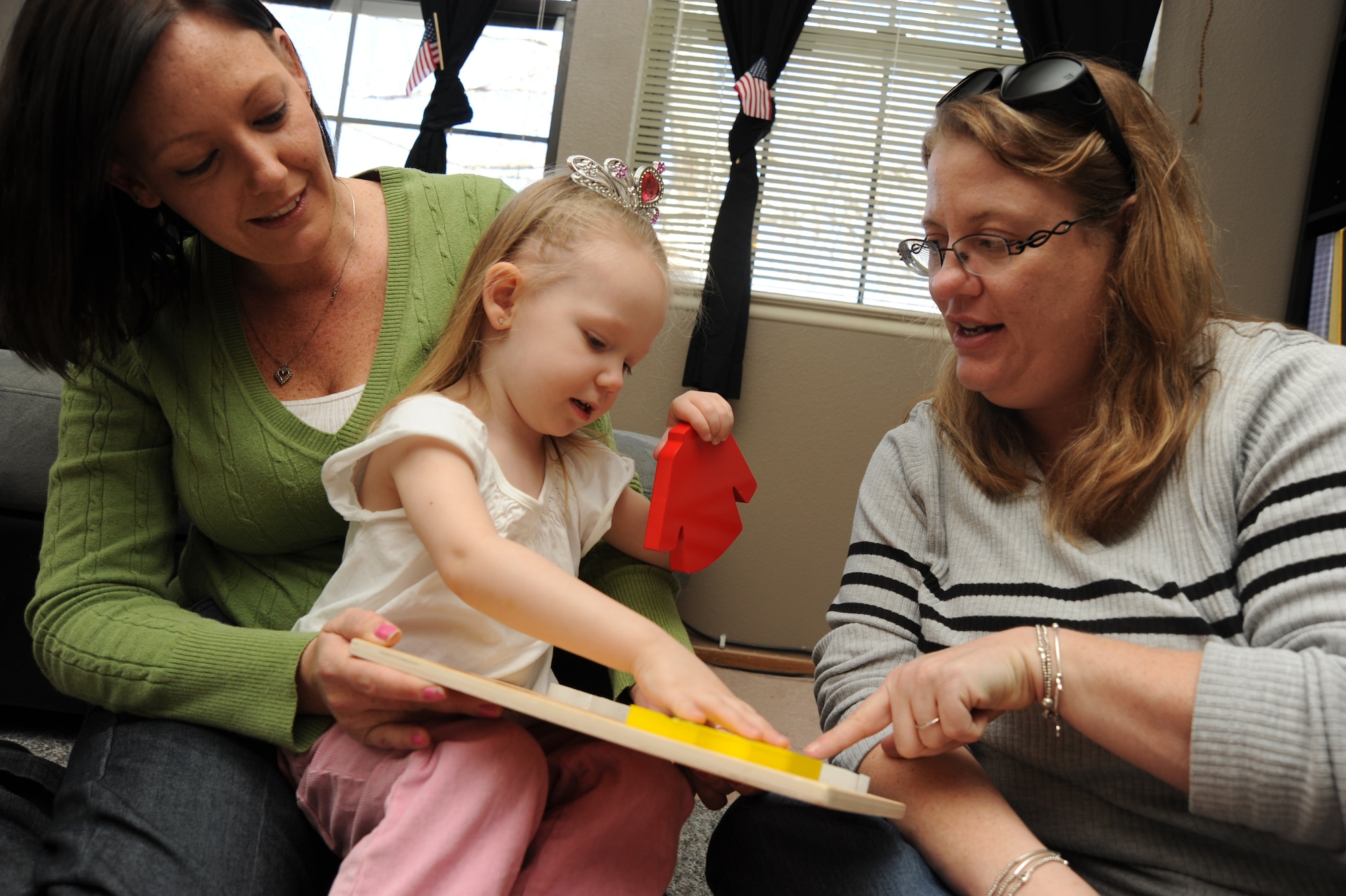 Team McConnell family member Tish Holmes holds her daughter, Savannah, 2, while she names colors of puzzle pieces for Stephanie Shellenbarger, a Parents as Teachers Heroes at Home educator, Nov. 25, 2009, at McConnell Air Force Base, Kan.  McConnell PATHAH program educators believe that parents are a child’s first teacher. PAT-HAH is a free program designed to help parents enhance their child’s development of language and social and intellectual growth during at home visits, parent group meetings and playgroups, and child screening. (U.S. Air Force photo by Tech. Sgt. Chyrece Campbell) 