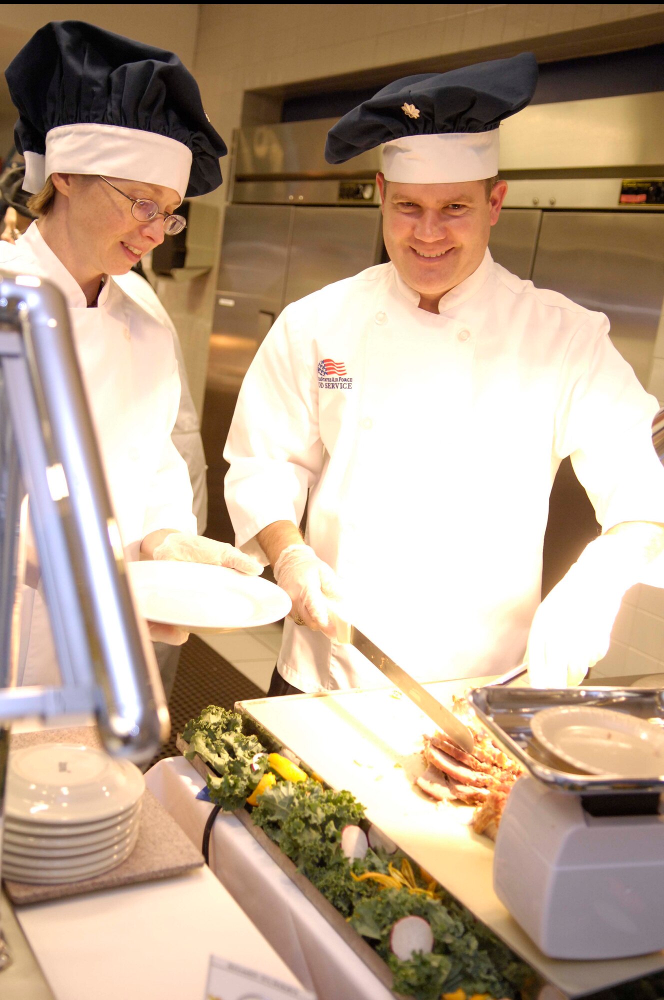 VANDENBERG AIR FORCE BASE, Calif. — Lt. Col. Elena Oberg, the 30th Launch Support Squadron commander,  and Lt. Col. Jason Bush,  the 30th Force Support Squadron commander , team up to serve turkey at Breakers Dining Facility for Vandenberg’s Thanksgiving Luncheon Thursday, November 26, 2009. The commanders are just a few of many who volunteered their time and services to provide the patrons with a Thanksgiving meal. (U.S. Air Force photo/Airman 1st Class Lael Huss) 