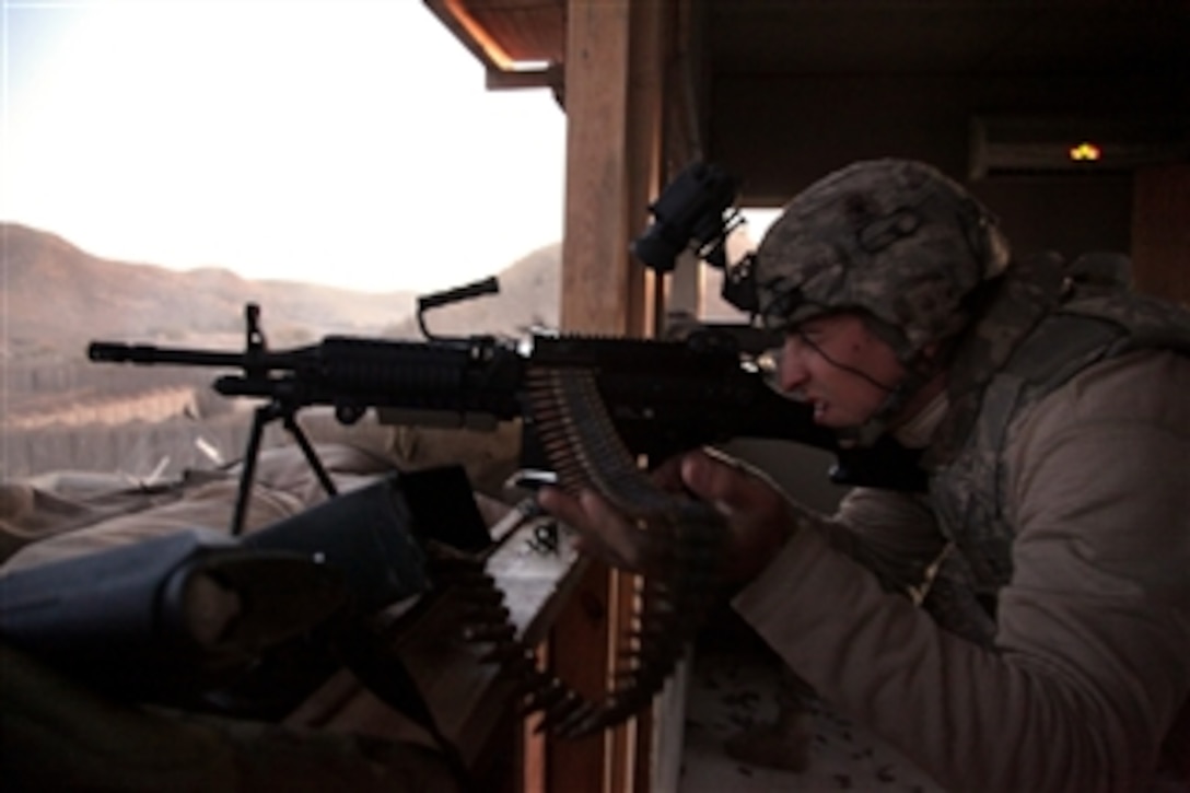 A U.S. Army soldier fires an M-248 machine gun after receiving enemy mortar fire at Combat Outpost Terezaye, Afghanistan, on Nov. 26, 2009.  