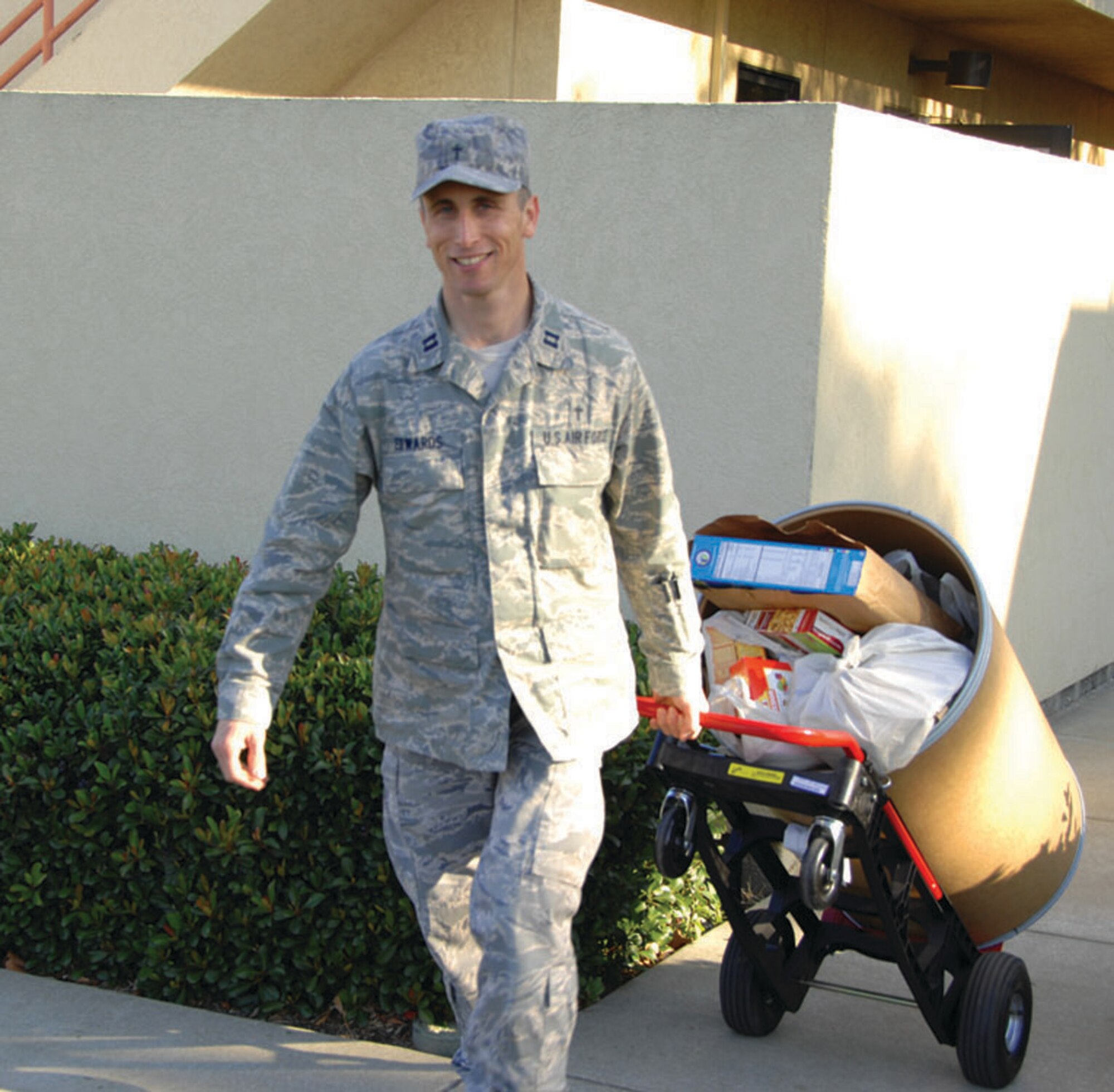 TRAVIS AIR FORCE BASE, Calif. -- Chaplain (Capt.) Andrew Edwards, 349th Air Mobility Wing chaplain, wheels a barrel of donated food out to be loaded on a truck for delivery to local charities who feed the hungry and the homeless and others in need. The wing chaplain’s office has spearheaded this food drive yearly.  (U.S. Air Force photo/Senior Master Sgt. Ellen Hatfield)