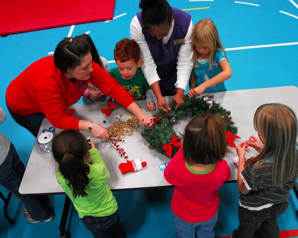 Children and workers with the Child Development Center and Youth Programs Center gather around a table to decorate a wreath at the Youth Programs Center here Dec. 1. The group was also joined by volunteers from the American Society of Interior Designers who helped children decorate the wreaths in support of the Festival of Wreaths and donation to the Medical University of South Carolina Children's Hospital. (U.S. Air Force photo/Staff Sgt. Daniel Bowles)