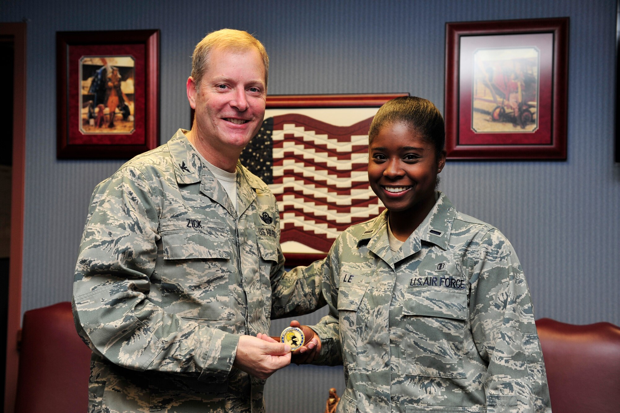 Col. Michael Zick, 19th Airlift Wing vice commander, presents 1st Lt. Jessica Le, 19th Medical Group deputy flight commander, with a coin Dec. 2 for being the combat airlifter of the week. Lieutenant Le expertly managed a $50 million food safety program and assessed food vulnerability levels, protecting more than 5,000 people of the base’s population. (U.S. Air Force photo by Airman 1st Class Lausanne Pacheco)