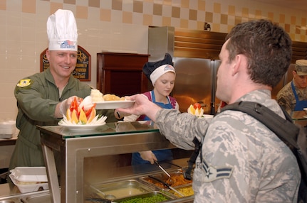 Col. John Wood serves Airman 1st Class Joe Pears a plate of food during the Thanksgiving dinner held at the Robert D. Gaylord Dining Facility here Nov. 26. A traditional Thanksgiving dinner with turkey, ham and all the fixings were served to active-duty military and their families. Colonel Wood is the 437th Airlift Wing commander and Airman Pears is a passenger service agent with the 437th Aerial Port Squadron. (U.S. Air Force photo/Staff Sgt. Marie Brown)