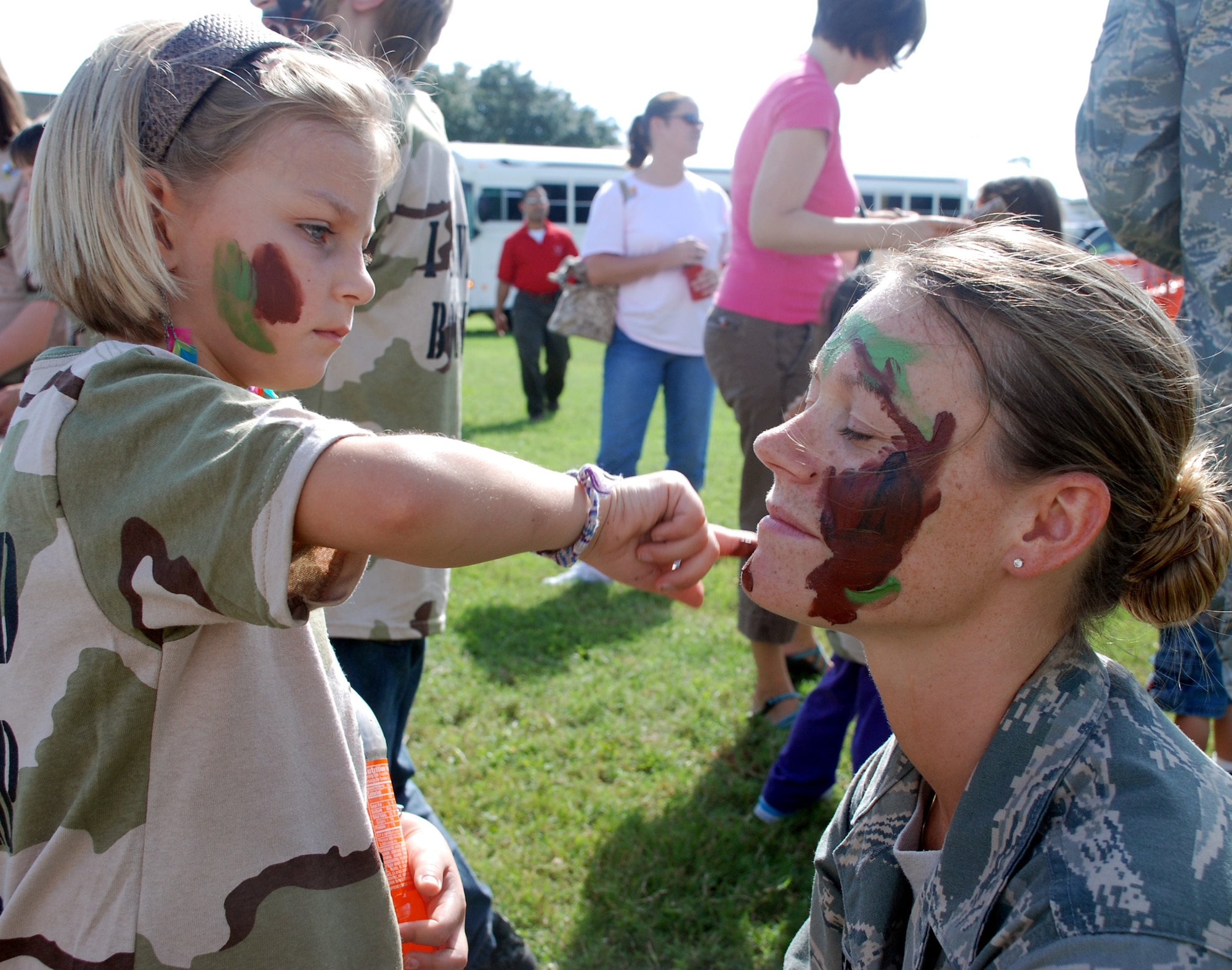 Senior Airman Cassandra Dameron, 81st Inpatient Operations Squadron, has her face “camoed” by 7-year-old Kylie Limrick, during Operation Hero.  Kylie is the author’s daughter.  (U.S. Air Force photo by Senior Airman Kimberly Moore)