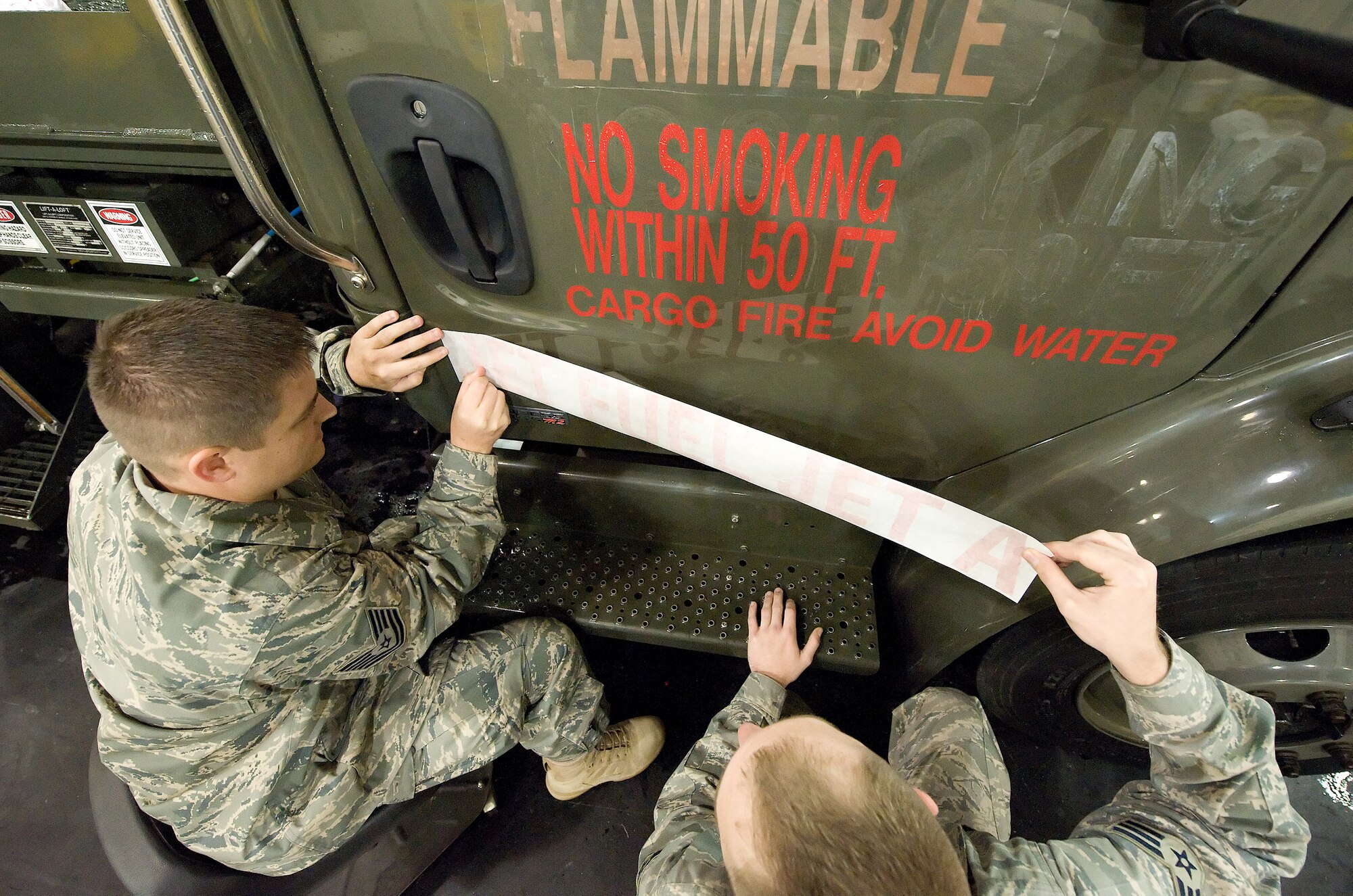 (From left) Tech. Sgt. David Jackson, 512th Logistics Readiness Flight, and Senior Airman Brandon Ancil, 436th Logistics Readiness Squadron, apply a Jet Fuel Jet A decal to a fuel truck at Dover Air Force Base.  Dover AFB is one of four Air Force installations testing and evaluating the use of Jet A in military aircraft to determine energy cost savings. This initiative is one of several examples of the direct mission support and innovative management displayed by the 436th LRS. (U.S. Air Force photo/Jason Minto)