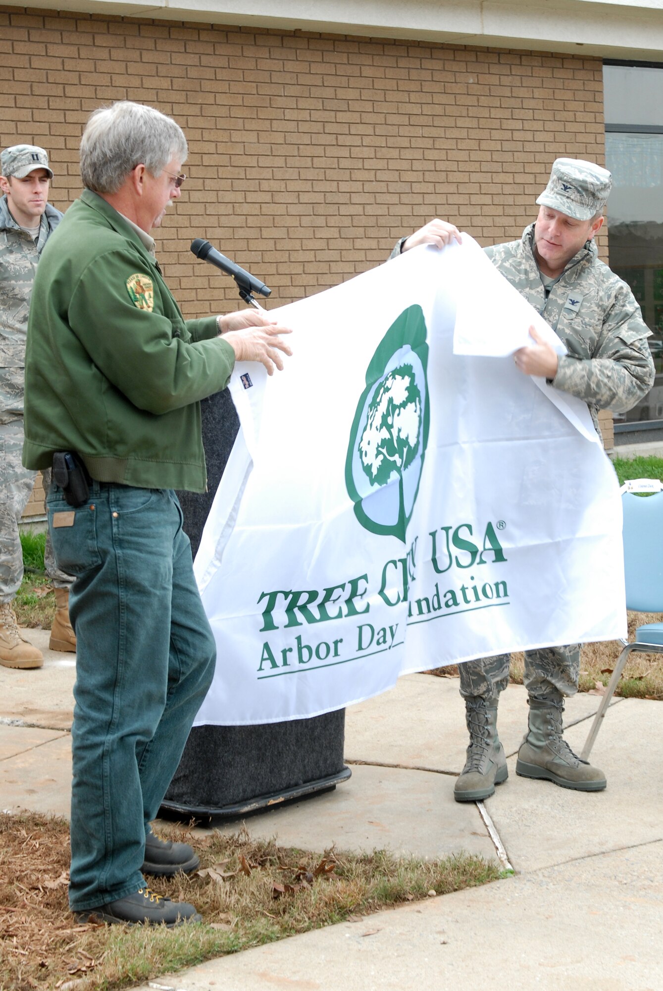 Ken Coley, Arkansas Forestry Commission assistant director, presents Col. Michael Zick, 19th Airlift Wing vice commander, with the Tree City USA flag Dec. 1 during the base’s Arbor Day ceremony held at the child development center. This is the 16th consecutive year Little Rock Air Force base has received the Tree City USA flag during the base’s Arbor Day celebration. (U.S. Air Force photo by Senior Airman Christine Clark)