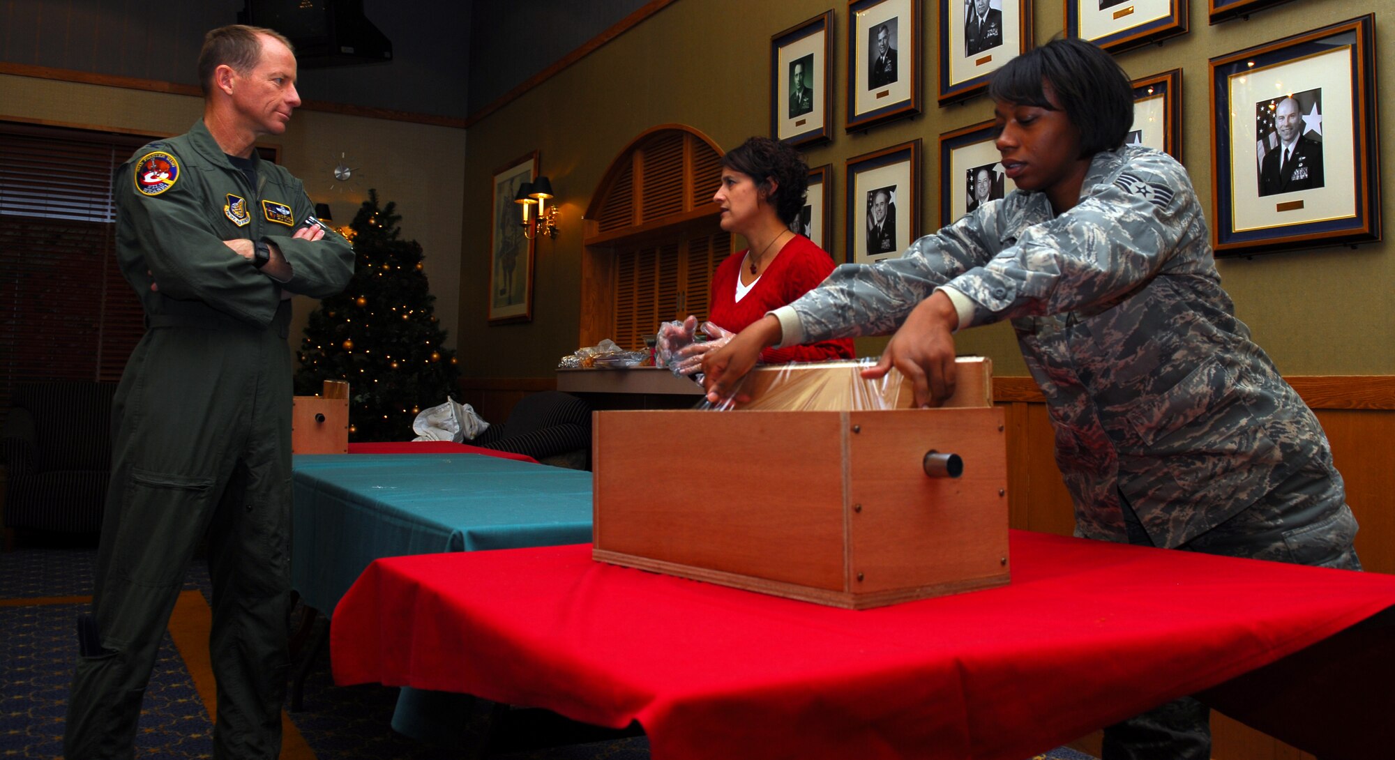 MISAWA AIR BASE, Japan—Christine Youtsey, wife of 35th Operations Group deputy commander, Lt. Col. David Youtsey , explains to Col. David Stilwell, 35th Fighter Wing commander, the proper procedures for wrapping cookies Dec. 2. Meanwhile, Staff Sgt. Takia Braddy, 35th Maintenance Squadron non-destructive inspection specialist, prepares for the next plate of cookies to wrap at the Collocated Club. Approximately 17,000 cookies were wrapped, producing almost 1,400 plates for single unaccompanied serve members. (U.S. Air Force photo/Staff Sgt. Phillip Butterfield)