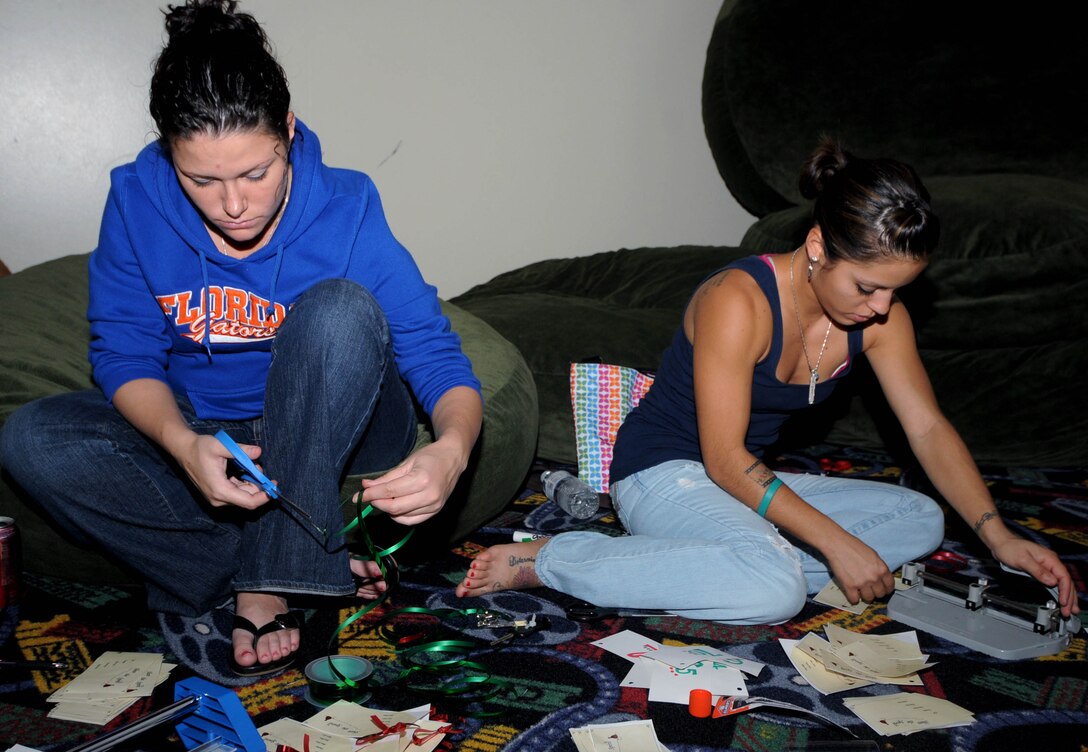 ANDERSEN AIR FORCE BASE, Guam - Senior Airman Robin Lumm, 644th Combat Communications Squadron Communication Focal Point Technician, and Senior Airman Vanessa Fuentes, 36th Wing Public Affairs Videographer, prepare sponsor cards here on Nov. 18th. Airman Lumm and Fuentes were volunteering in support of Team Anderson's First Four's "Share the Spirit" holiday season toy drive. The drive will help underprivileged youth in the Guam community. ( U.S. Air Force Photo by Airman 1st Class Julian North) 