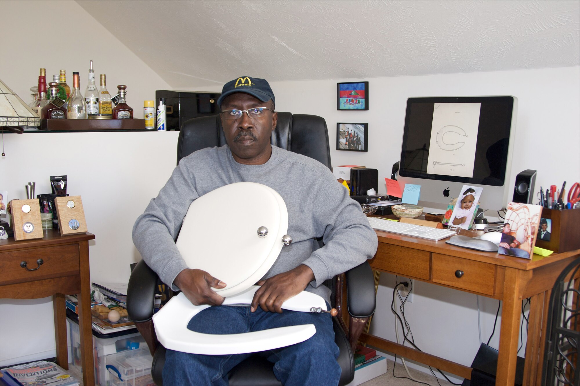 Charles Easley sits in his workshop at home, holding a specialized toilet seat for residential use, one of two inventions he was able to get a patent on since 1992. He has other patents pending.  (Photo provided)