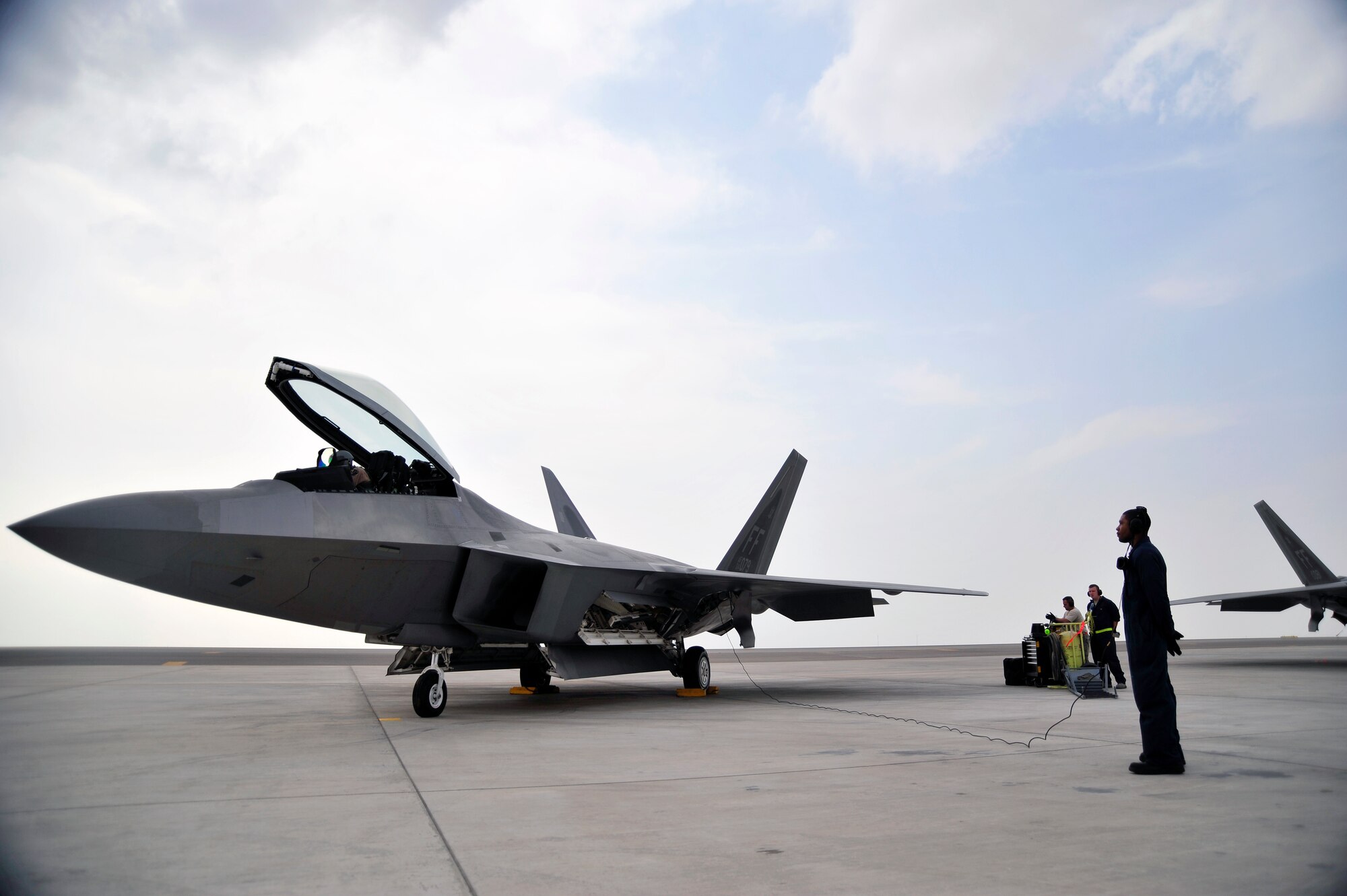 UNITED ARAB EMIRATES AIR WARFARE CENTER, UAE - Senior Airman Deandre Barnes, 1st Fighter Wing crew chief, awaits orders from Capt. Blaine Jones, First Fighter Wing F-22 Raptor pilot, Nov. 30, 2009. Airman Barnes and Captain Jones are on temporary duty from Langley Air Force Base, Va. Airman Barnes hails from Jacksonville, Ark., and Captain Jones hails from Kingman, Kan. F-22 Raptors have deployed from the 1st Fighter Wing at Langley AFB, VA to the United Arab Emirates Air Warfare Center.  Aircrews have been participating in bilateral training opportunities with Coalition partners.  The exercises are designed to promote security, stability and mutual interests in the region.  (U.S. Air Force photo/Tech. Sgt. Charles Larkin Sr)
