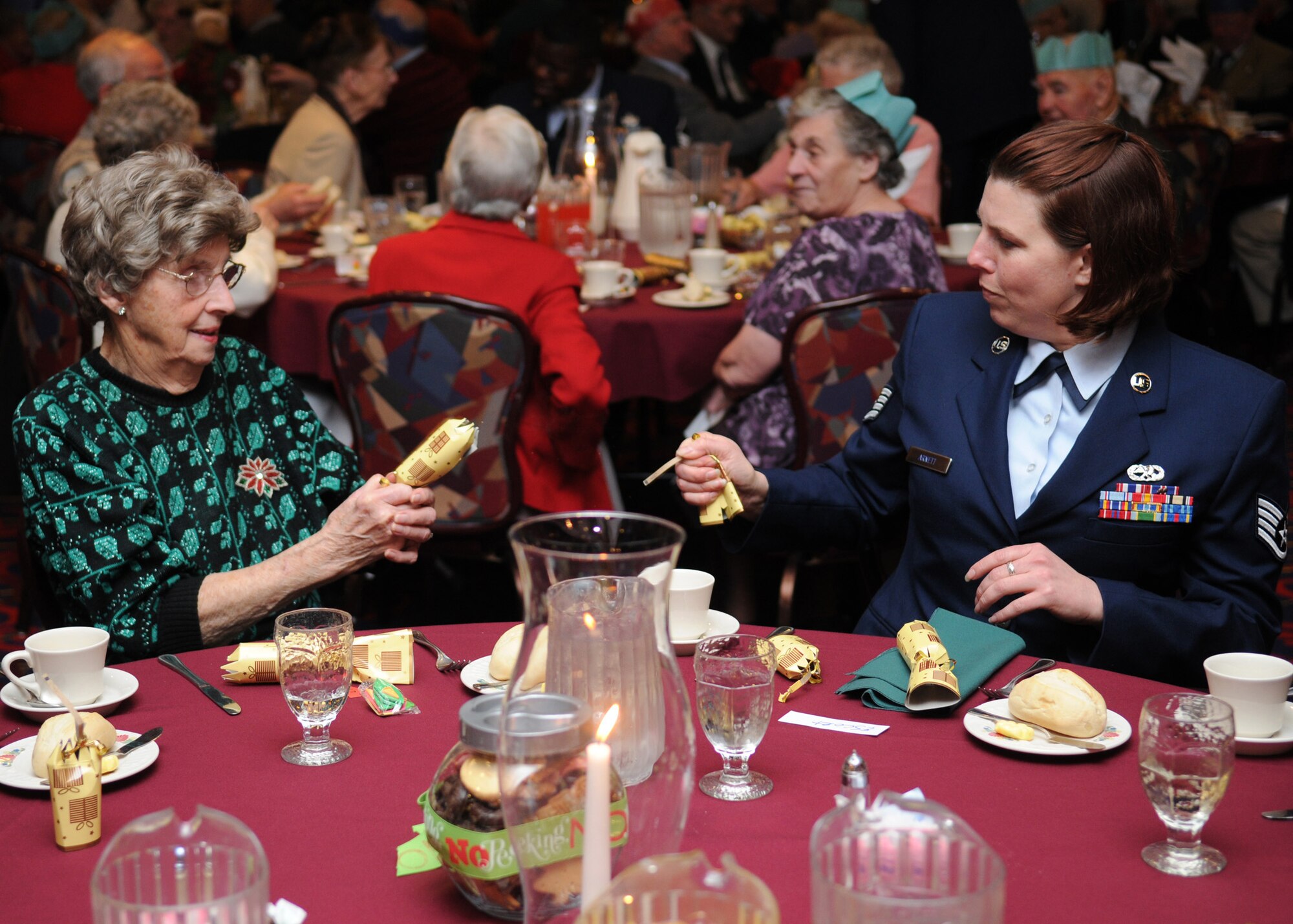 RAF MILDENHALL, England – Joan Aves and Staff Sgt. Wendy Arnett, 352nd Maintenance Squadron, open Christmas crackers during the Senior Citizens Christmas Luncheon at the Galaxy Club Dec. 2. The event gives senior citizens in the local area an opportunity to have lunch, play games and meet new people. (U.S. Air Force Photo/ Staff Sgt. Jerry Fleshman) 