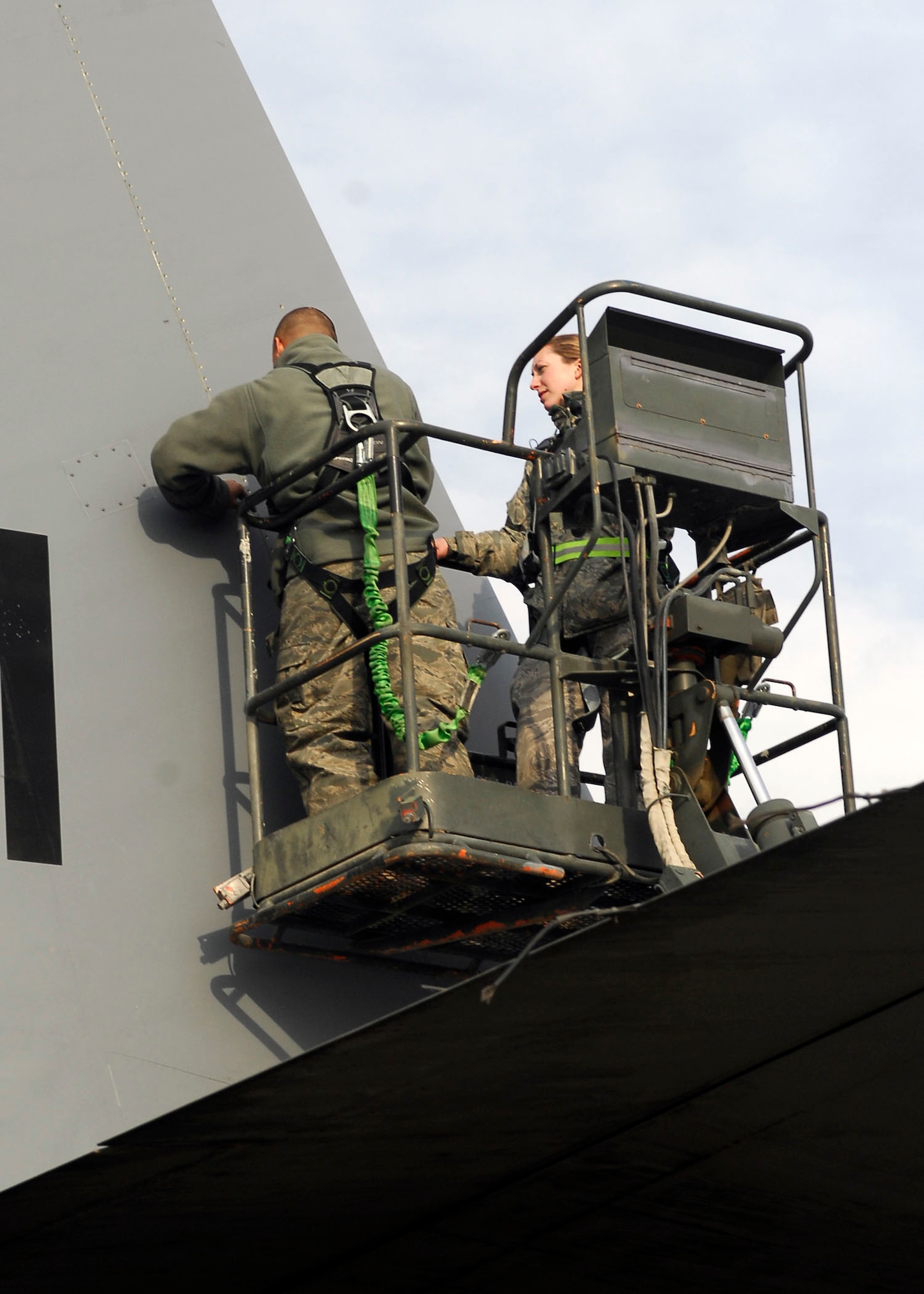 BAGRAM AIRFIELD, Afghanistan -- Tech. Sgt. Lee Fortner removes screws from a panel on the EC-130 Compass Call so the aircraft can be inspected, while Airman First Class Sarah Garrett moves the lift when needed, Dec. 3, 2009.  These inspections are important because the EC-130?s primary mission is to support tactical air operations.  Both Airmen are from the 41st Expeditionary Electronic Combat Squadron deployed from Davis-Monthan Air Force Base, Ariz.  Sergeant Fortner, a crew chief, hails from Las Vegas.  Airman Garrett, an electronic warfare specialist, hails from Alamogordo, N.M.  (U.S. Air Force photo/Senior Airman Felicia Juenke)