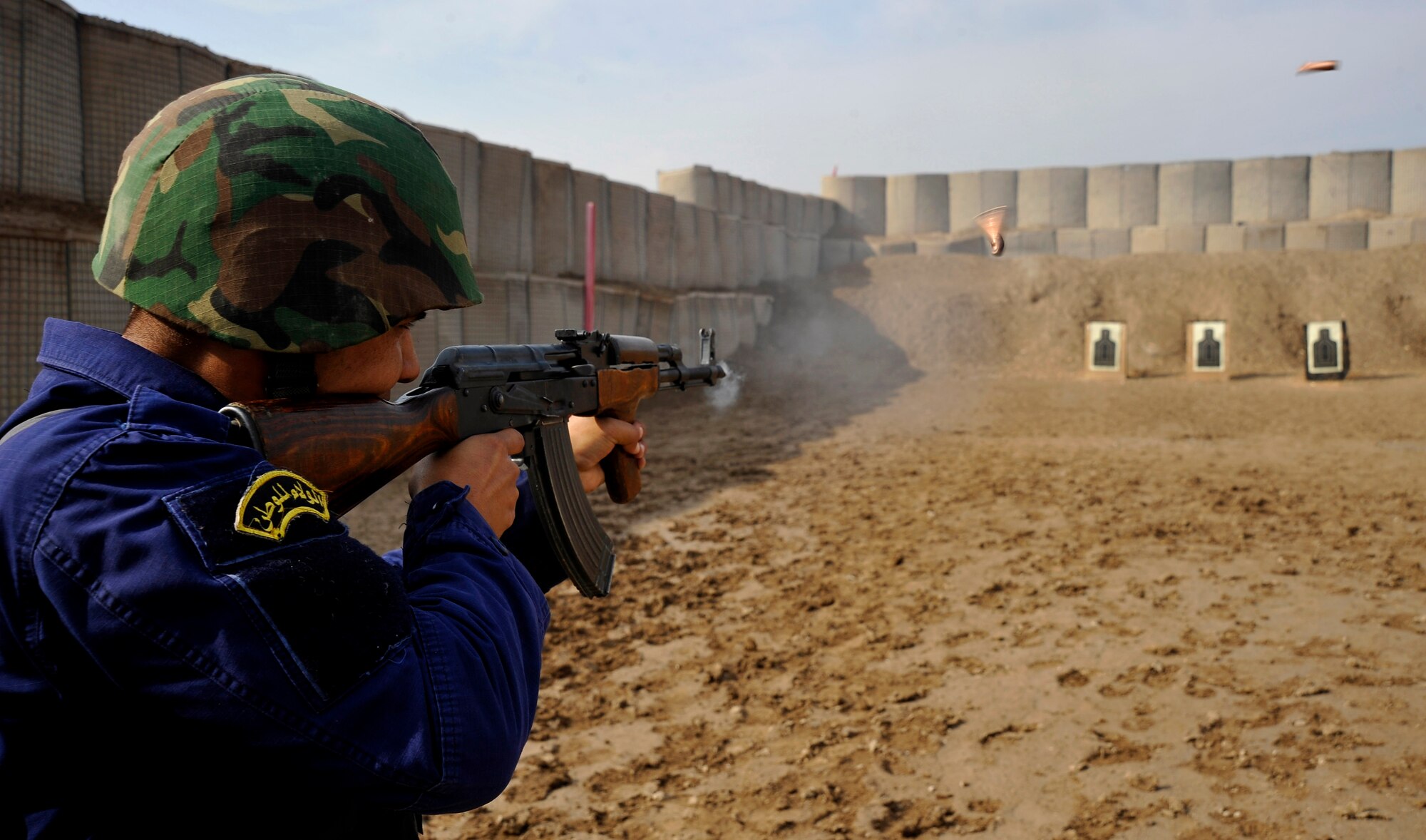 An Iraqi Police officer shoots downrange at his target after recieving instructions from U.S. Air Force Staff Sgt. Michael Gomez, 732nd Expeditionary Security Forces Squadron Det. 2, deployed to Baghdad, Iraq,  Nov. 18, 2009. (U.S. Air Force photo/Staff Sgt. Angelita Lawrence)
