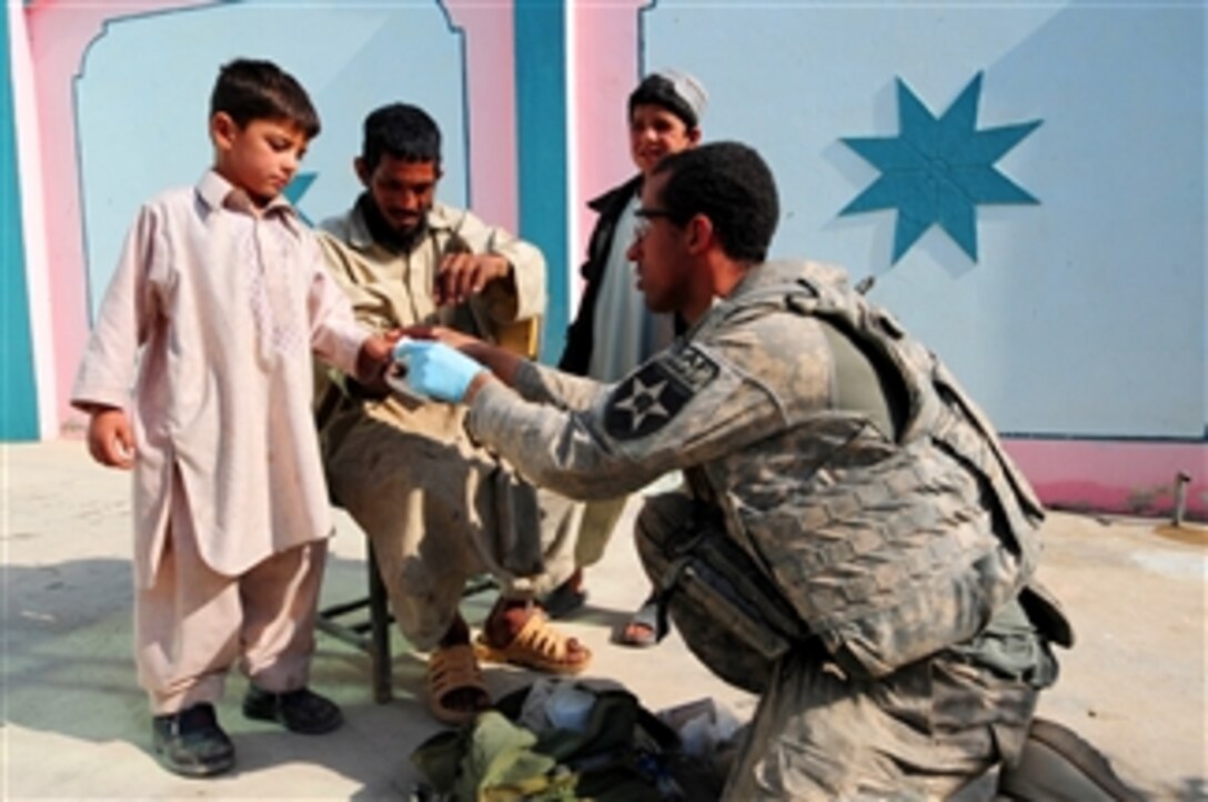 U.S. Army Spc. Lemont Chambers, a medic with Charlie Company, 1st Battalion, 17th Infantry Regiment, 2nd Infantry Division, bandages the hand of an Afghan boy in Rajankala, Afghanistan, on Nov. 28, 2009.  Charlie Company is focused on providing humanitarian aid and support to Afghan citizens.  