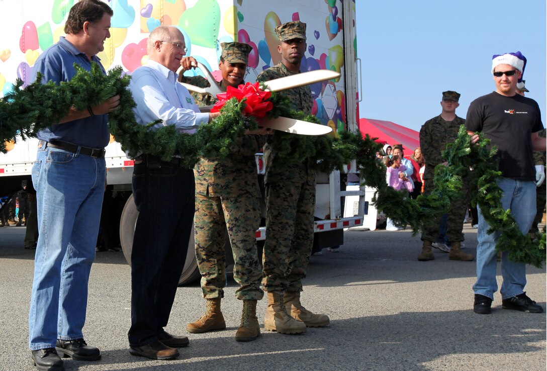 Sgt. Maj. Ramona D. Cook (holding scissors), Marine Corps Base Camp Pendleton sergeant major and Steve Drake (second to left), Christmas Spirit Foundation chief executive officer, kick off the Trees for Troops event at Camp Pendleton’s 16 Area Landing Zone, Dec. 3. Trees for Troops is a program designed to deliver support and festive cheer to service members and their families during the holiday season.