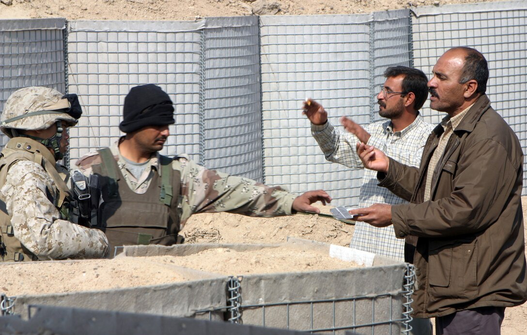 Fallujah, Iraq -- Lance Cpl. John Thor along with two Iraqi Security Force members work with locals who approached their post.  Working together and training the ISF, the Marines of 3D Battalion, 8th Marine Regiment helped prepare the Iraqi's to be better able to take over security for their country.  Official U.S. Marine Corps photo  by Lance Cpl. Athanasios L. Genos