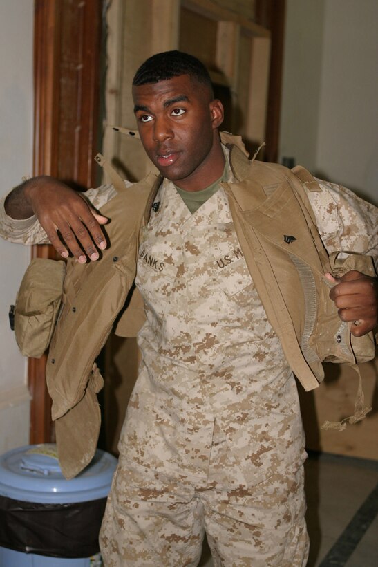 Sergeant Cryst Banks, a 21-year-old personnel administration clerk, Washington D.C. native and 2d Marine Division Morale Welfare and Recreation liaison gets his flak jacket on to go talk to some of his contacts to arrange for entertainment on the camps to boost morale.  U.S. Marine Corps photo by Sgt. Stephen D'Alessio (RELEASED)
