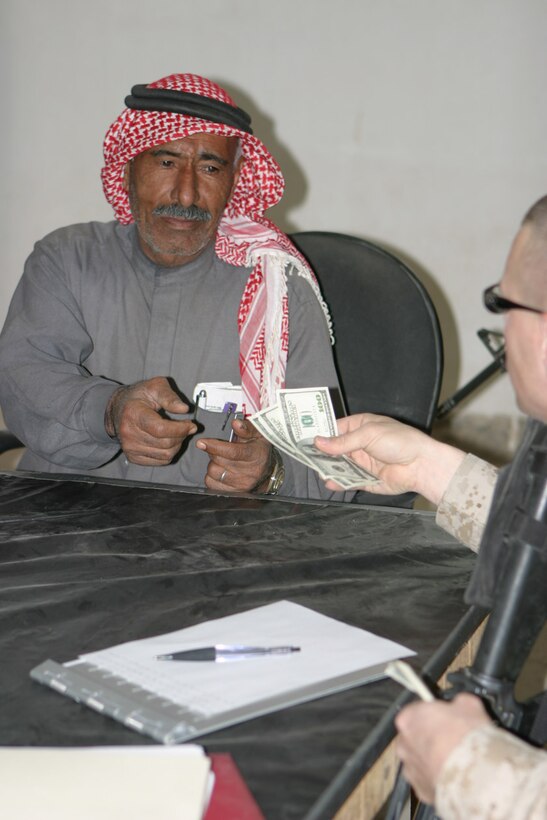 CAMP FALLUJAH, IRAQ – A local Iraqi civil servant signs his name, documenting he has received his payment for his services provided.  Over 200 locals showed up and received payment for their jobs.  Official U.S. Marine Corps photo by Lance Cpl. Athanasios L. Genos