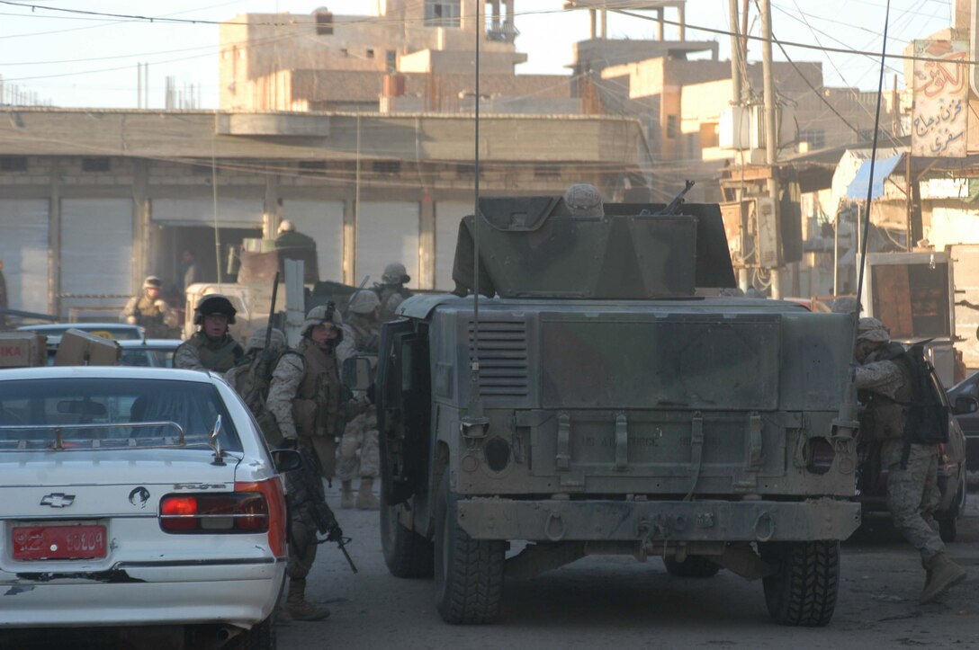 AR RAMADI, Iraq (March 18, 2005) - Marines with Company A, 1st Battalion, 5th Marine Regiment jump out of an up-armored humvee and spring into action on the congested streets of the marketplace here. The devil dogs patrolled the area in an effort to become more familiar with their area of operations and make their presents know to the local populace. The Marines also searched several building and a nearby mosque for weapons caches and insurgents. The three-hour patrol ended with the Marine returning empty handed to their base camp at Hurricane Point. Photo by Cpl. Tom Sloan