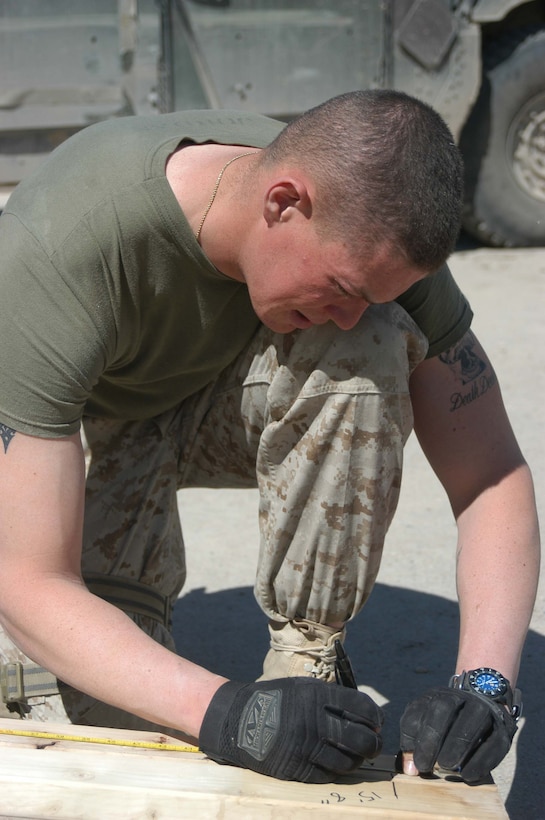 CAMP HURRICANE POINT, Ar Ramadi, Iraq (March 18, 2005) -Twenty-year-old Lance Cpl. Brandon C. Jordan, combat engineer, 1st Combat Engineer Battalion, from Hubert, N.C., marks a measurement on a two-by-four that will be used to build a chain-link roof for the 1st Battalion, 5th Marine Regiment's mailroom here. Construction work and carpentry are not uncommon for the combat engineers with 1st CEB. They also accompany different infantry companies on patrols where they conduct weapons caches sweeps and look for improvised explosive devices. Photo by Cpl. Tom Sloan