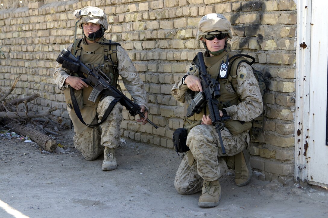 A Marine with 1st Battalion, 6th Marine Regiment and his field radio operator stop to provide security at a street corner here when their patrol stopped to rest for a few minutes.  1st Battalion, 6th Marine Regiment is currently deployed here to conduct security and stability operations.