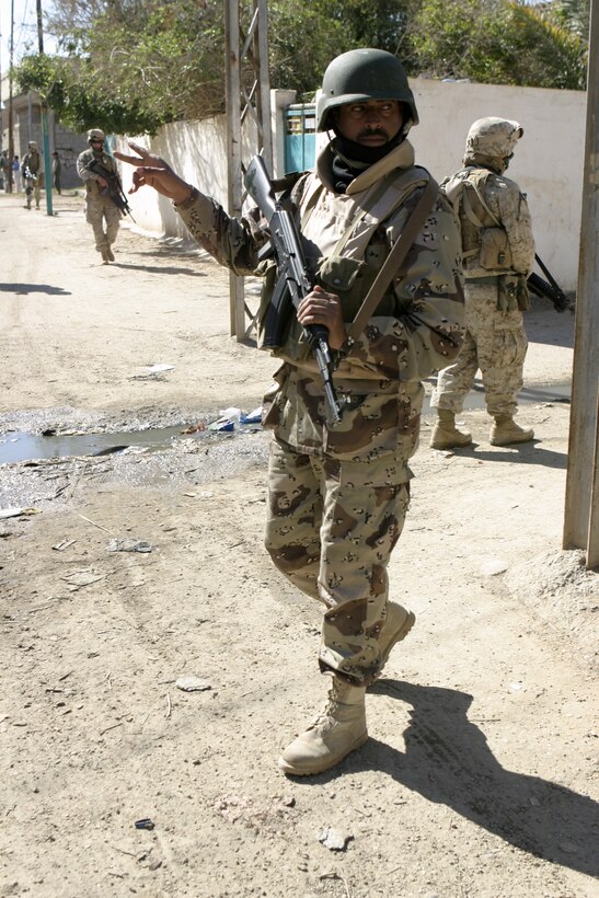 FALLUJAH, Iraq - A soldier with the Interim Iraqi Forces checks over his shoulder while patrolling the city streets with Marines of Company C, 1st Battalion, 6th Marine Regiment.  The local security forces work hand in hand with 1st Battalion, 6th Marine Regiment personnel to provide security and stability to Fallujah's residents.
