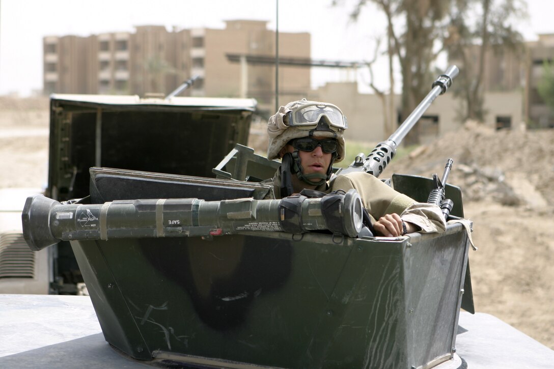 FALLUJAH, Iraq - A Marine with 1stBattalion, 6th Marine Regiment's Personal Security Detail Platoon peeks out from behind his vehicle's gun turret.  PSD performs missions such as escorting the battalion commander throughout the city, working alongside infantry companies to conduct raids, and patrolling Fallujah's streets in search of insurgent activity.