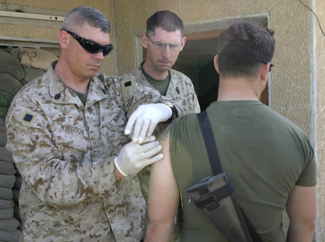 FALLUJAH, Iraq - Navy Chief Petty Officer Nathan Whiddon, 1st Battalion, 6th Marine Regiment's medical chief, administers shots to a Marine from Company B, 1st Battalion, 6th Marine Regiment at the company's base of operations here April 8.  Personnel from the Battalion's Aid Station travel as part of the 'XO's Road Show,' a Headquarters and Service Company convoy that travels once a week to the battalion's infantry companies' bases in Fallujah to offer the grunts services such as motor transport and communications equipment repair, religious services, and administrative and legal support.